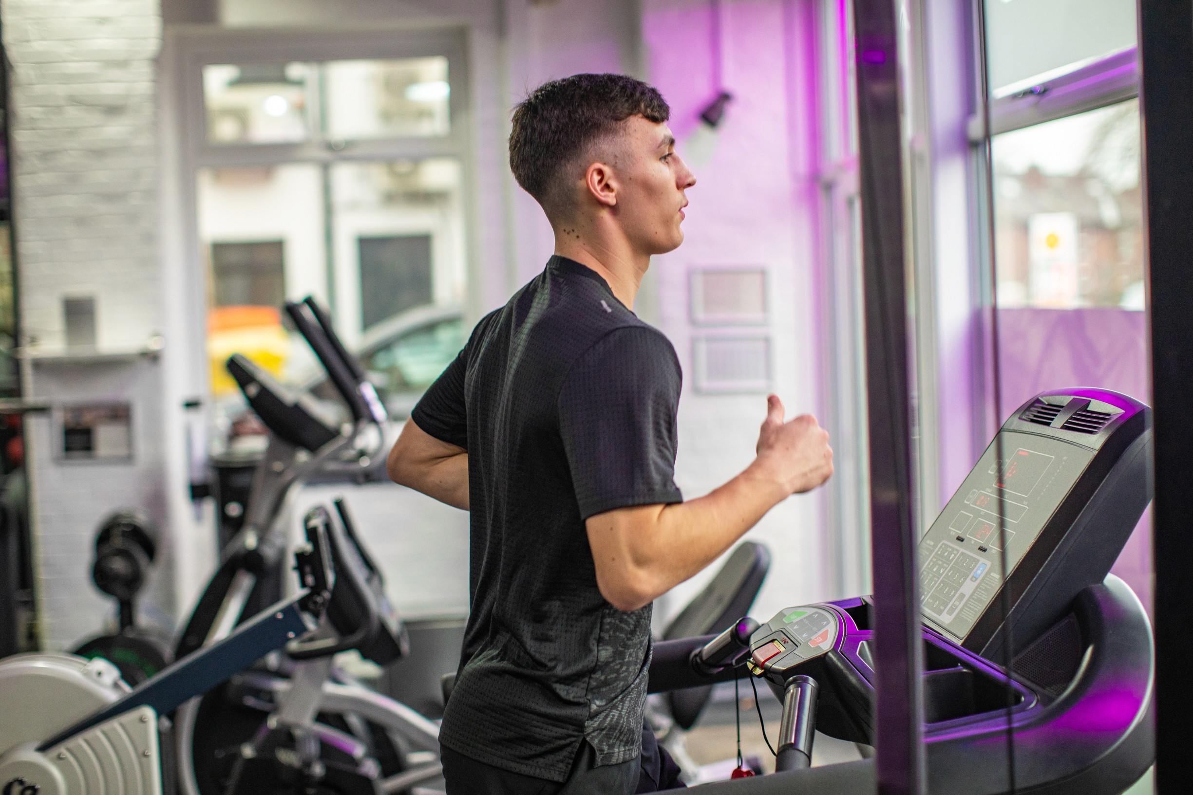 Man in gym clothes running on a treadmill, a great form of cardio exercise.