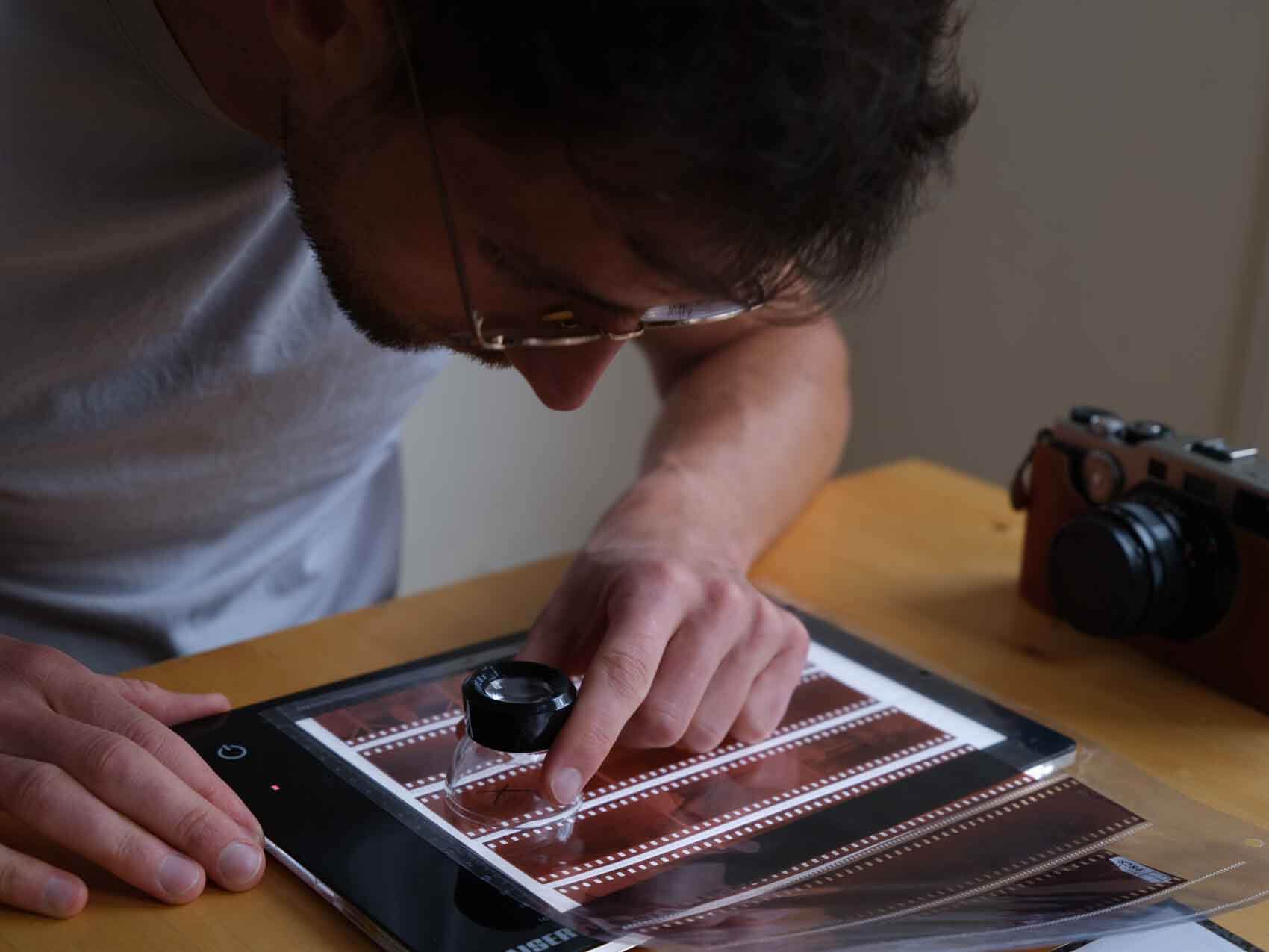 Inspecting analogue 35mm film on a Lightbox with a magnifying glass