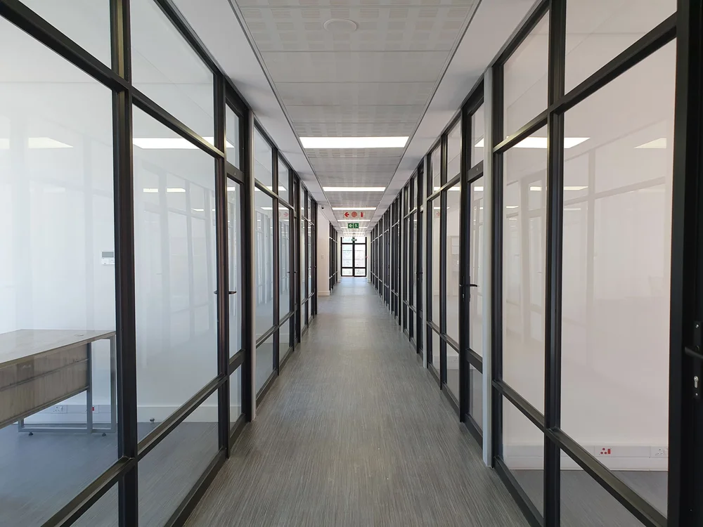 Blurred figure walking past a white wall with architectural sketches and photos on display.