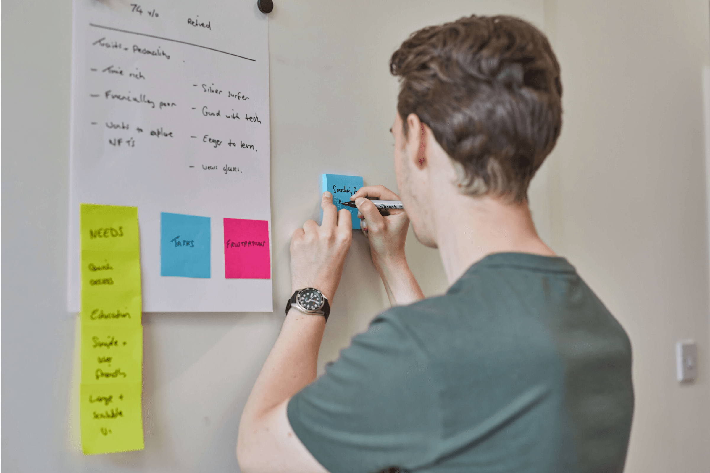 One of the designers writing on a post-it note against a white wall