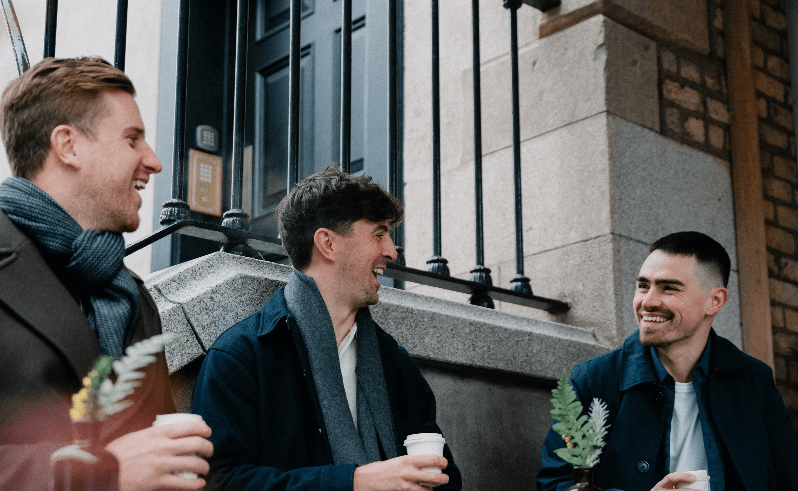 Three professionals smiling while walking outside office building – CSM consultation call-to-action banner.