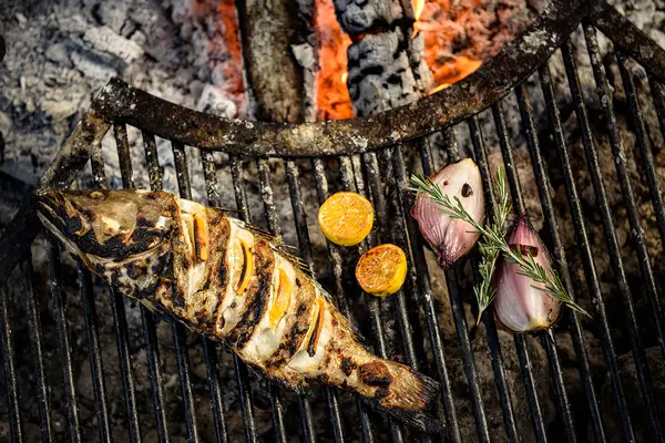 Grilled fish cooked over charcoal with lemon slices and garlic at 4 Fuegos restaurant, Be Tulum.