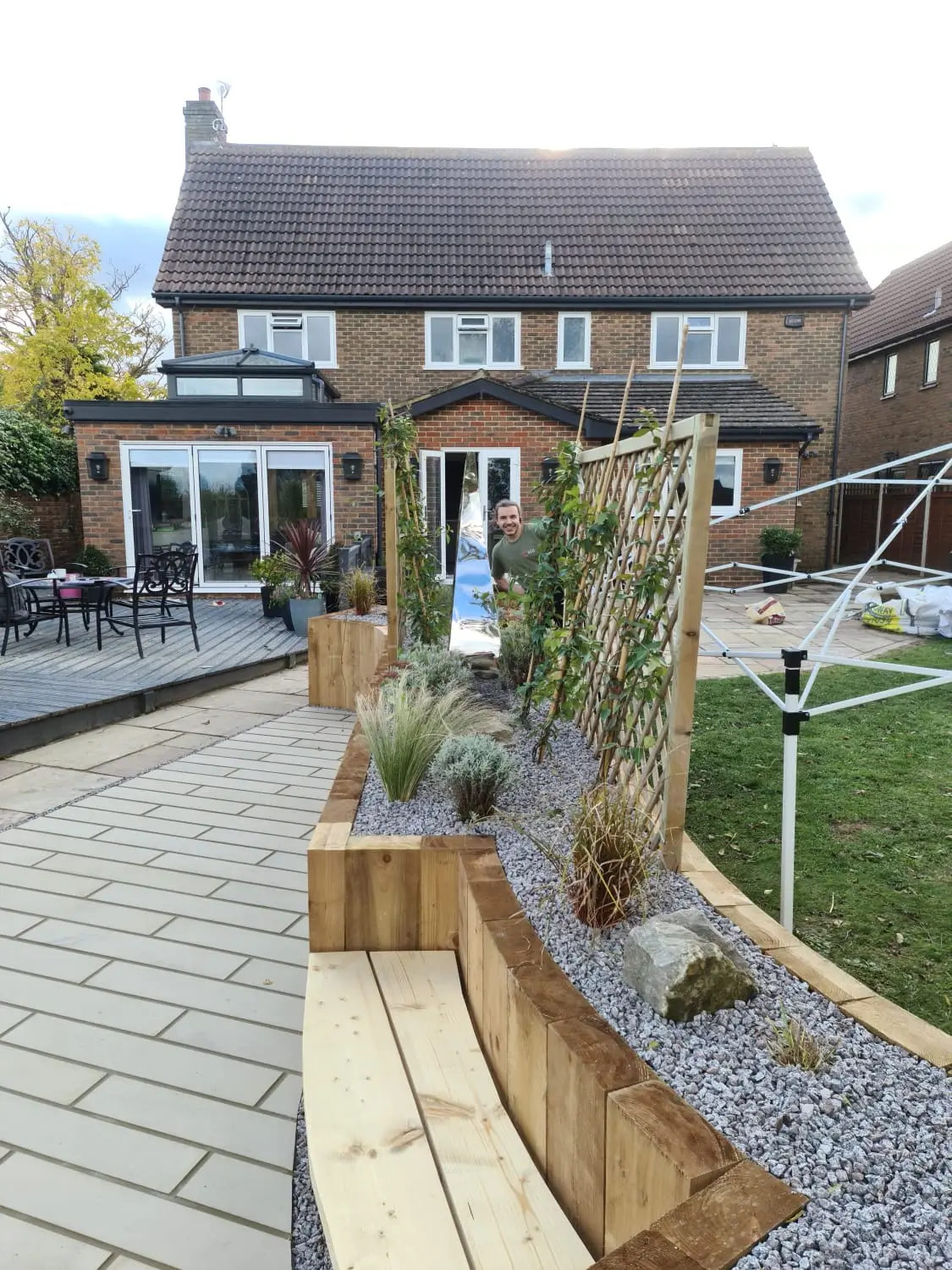 A garden pathway leads to a stone house with a well-maintained lawn and decorative planters along the path.