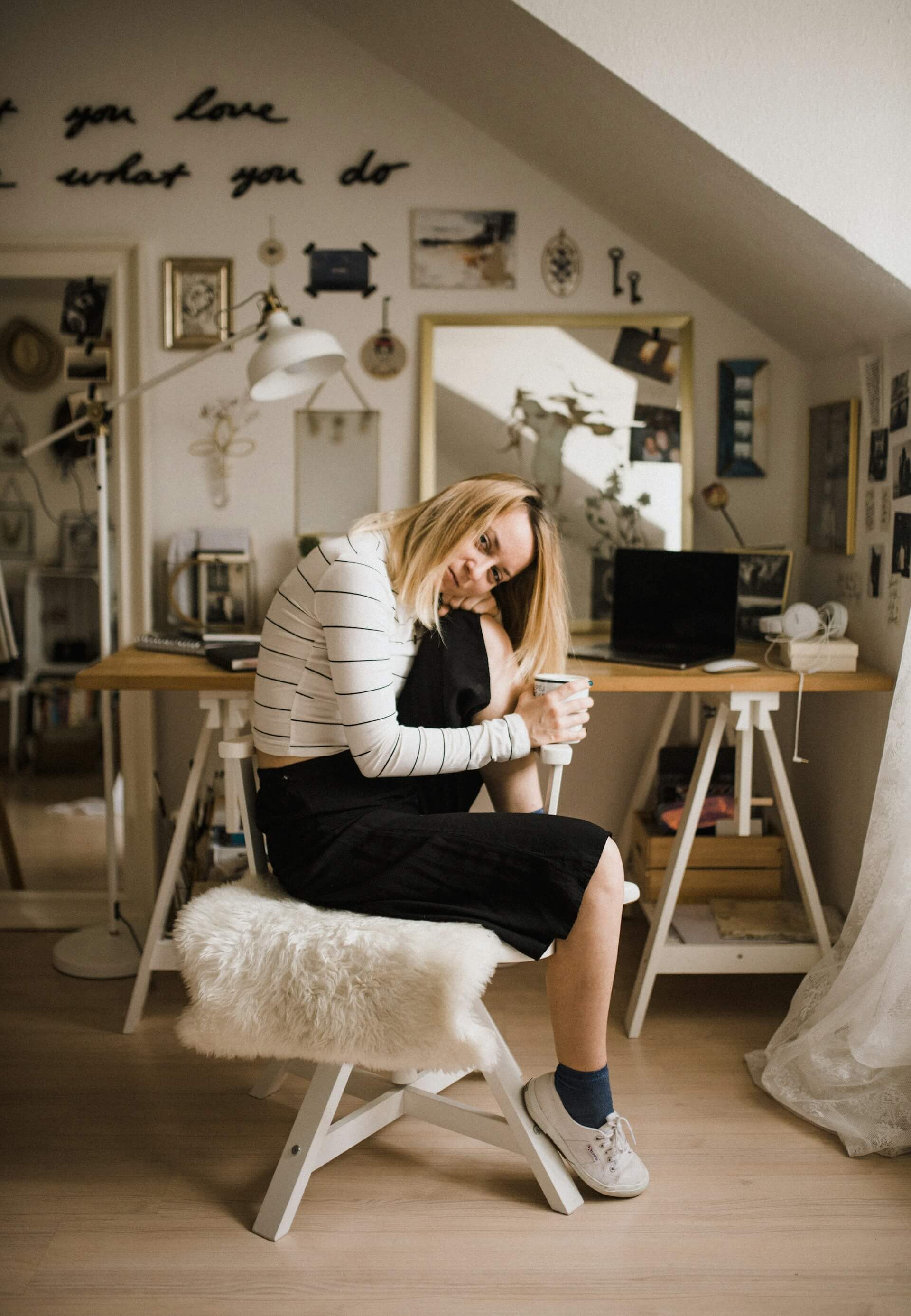 A woman seated in a chair at her home office, focused on her work amidst a cozy and organized environment