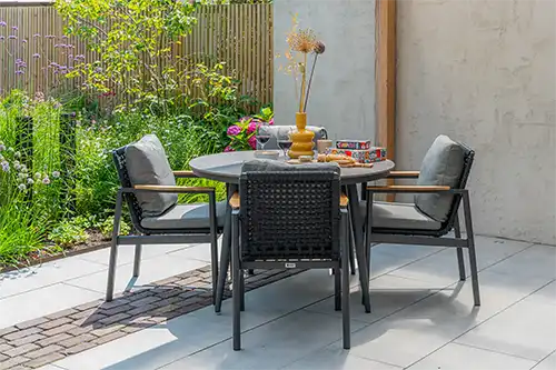 Elegant outdoor dining setup featuring Ralph COCO garden furniture surrounded by lush greenery.