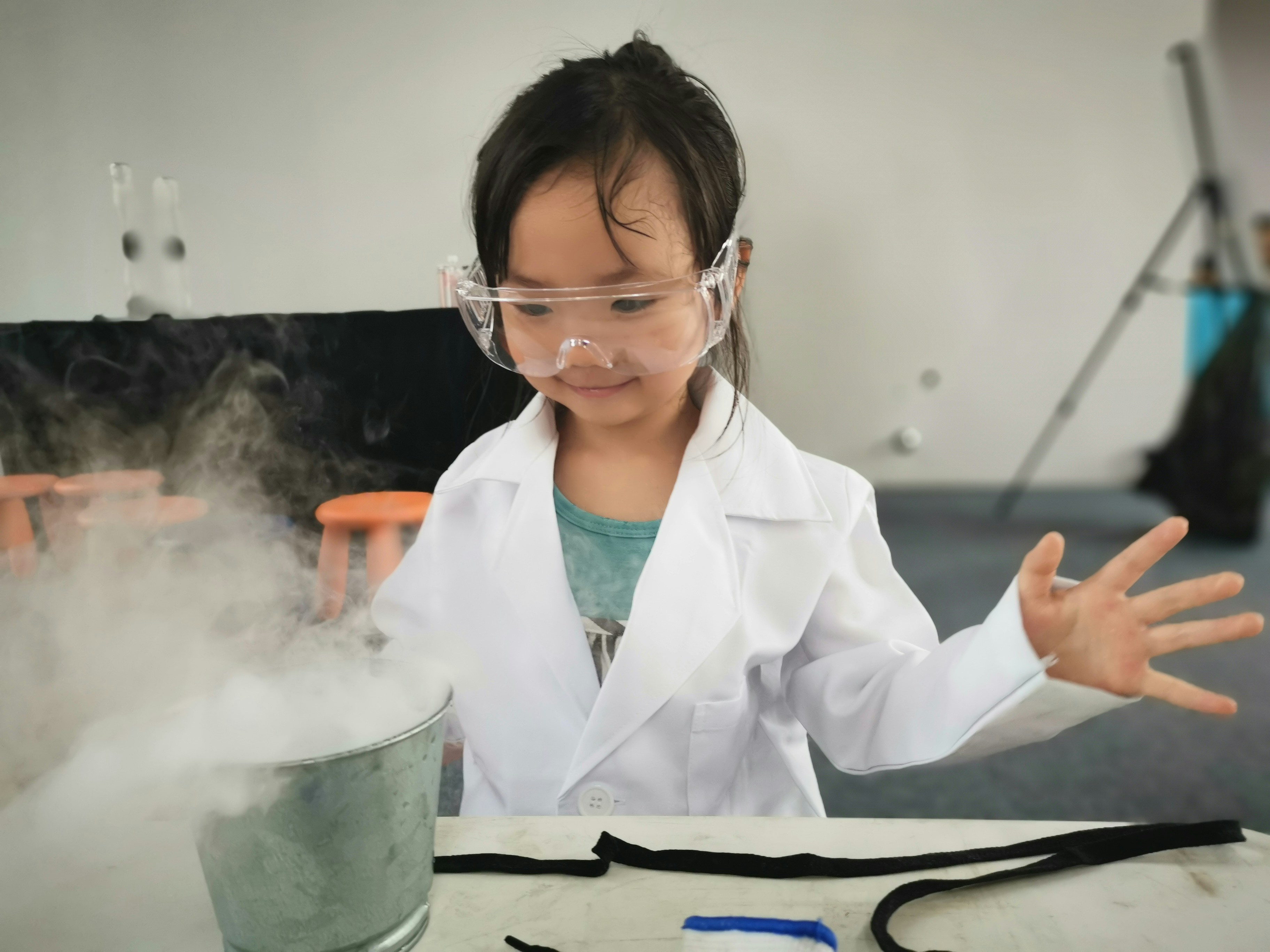 a little girl wearing a white lab coat and goggles