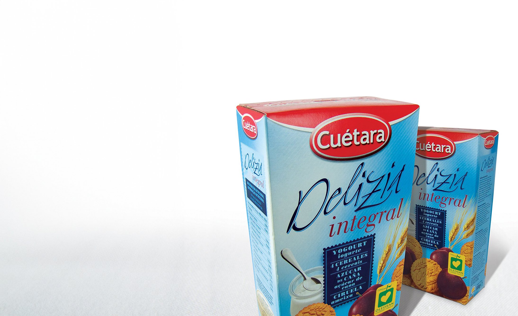 Se muestran dos cajas de galletas Cuétara Delizía Integral contra un fondo blanco. El embalaje presenta imágenes de trigo, yogur y ciruelas, lo que sugiere ingredientes saludables.