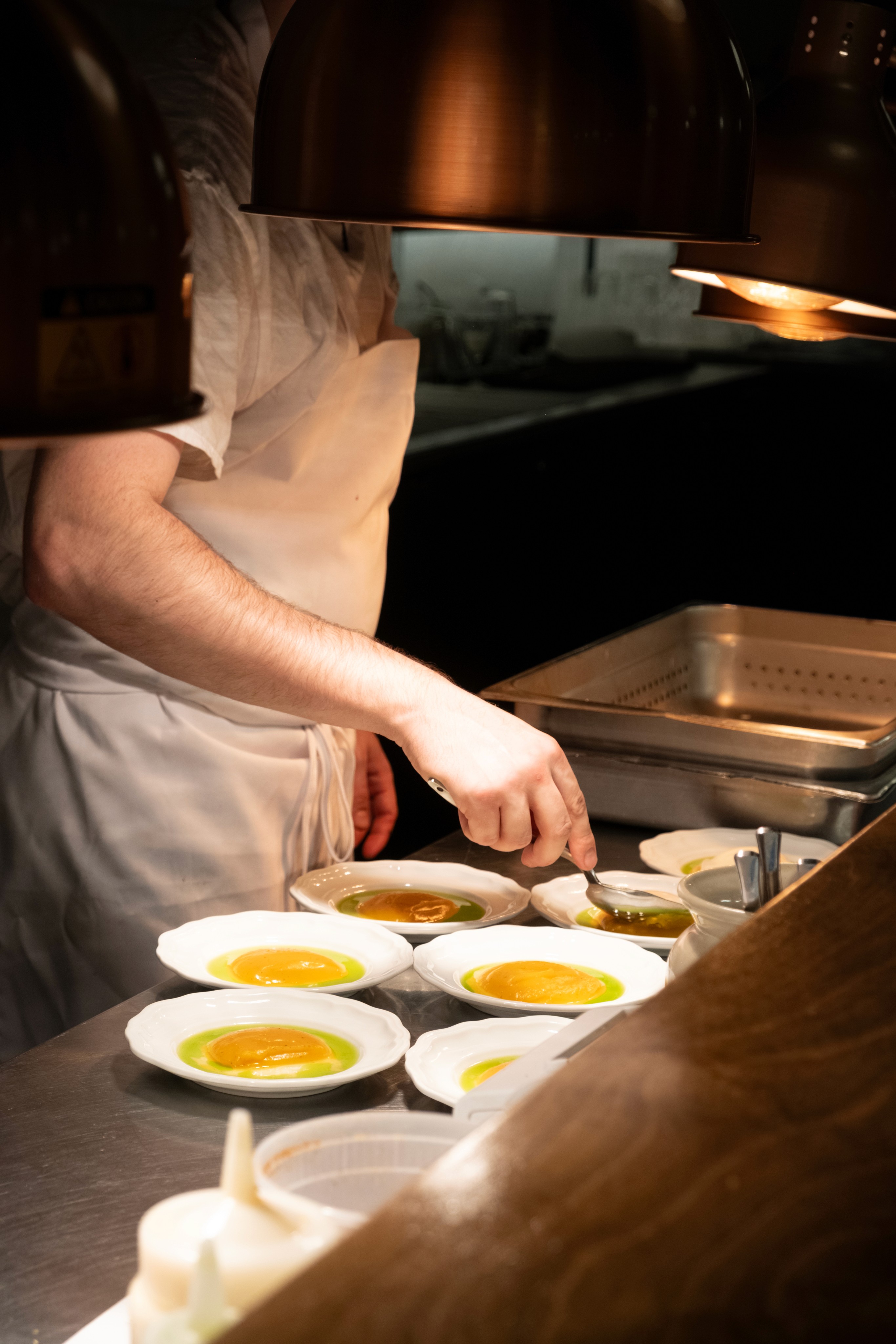 Un cuisinier prépare les accompagnements de purée de courge et oeuf mollet.