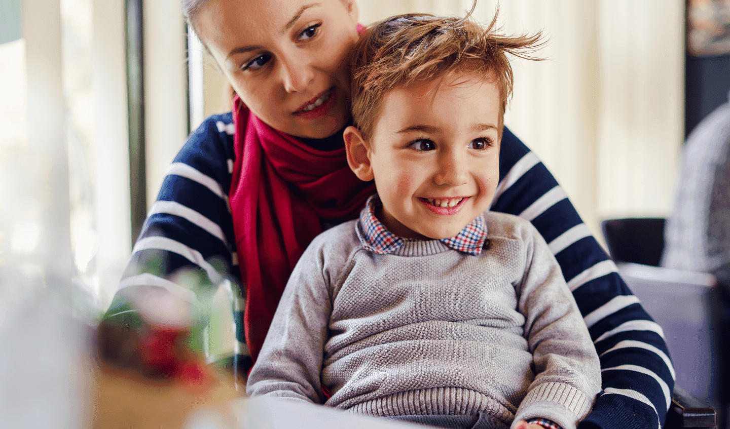 Smiling child sitting with an adult, representing family-centred healthcare and wellbeing.