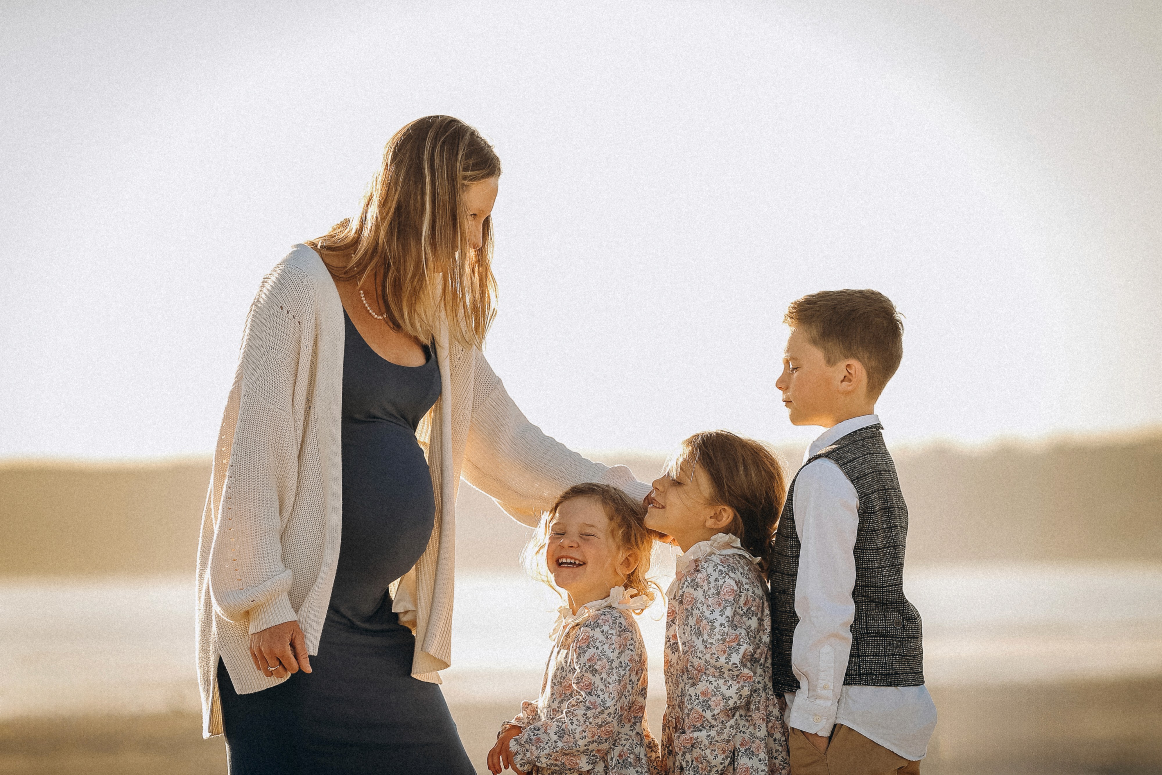 Mom standing with her children on the beach during a warm sunset family session