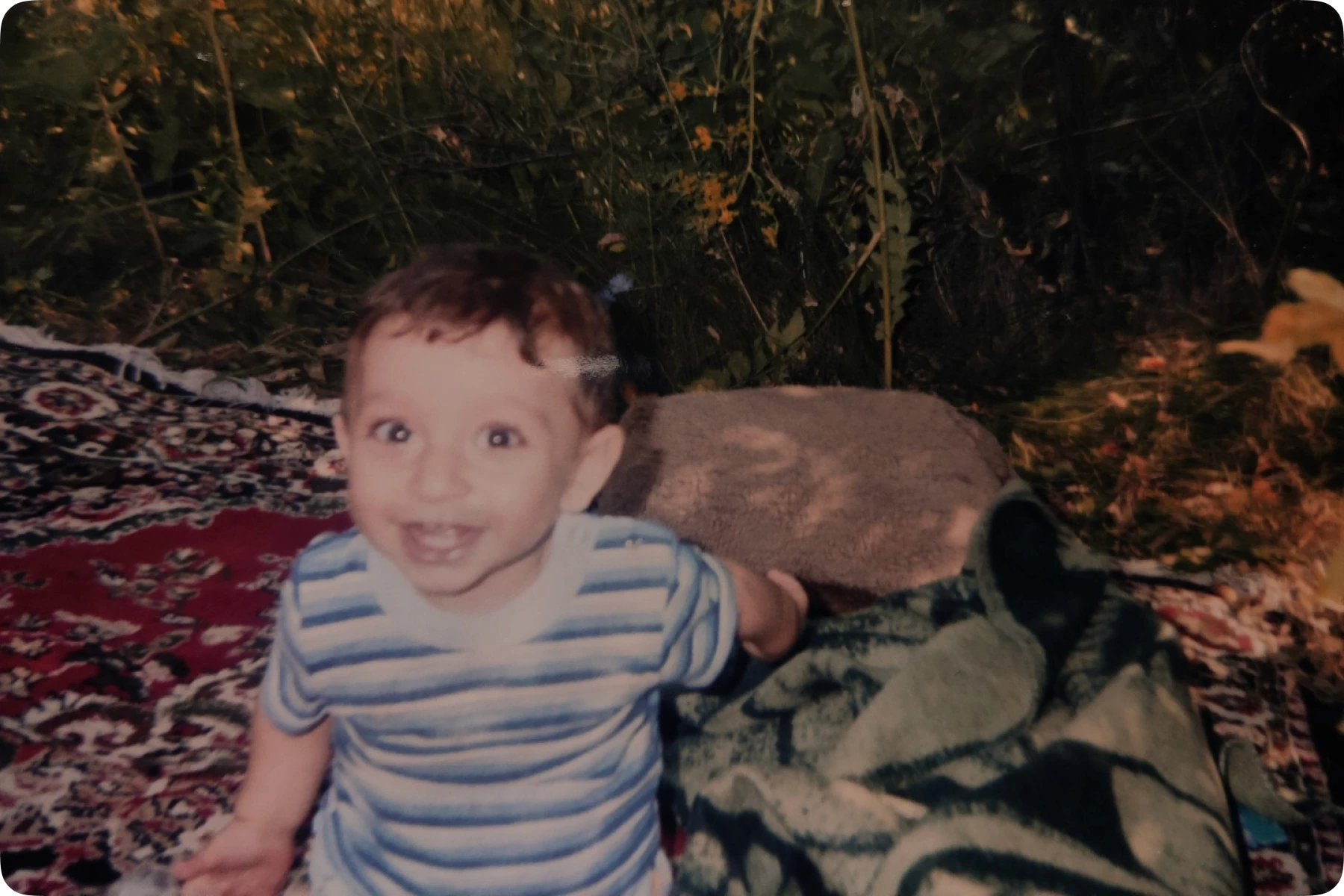 Childhood photo of Askiva founder Khayal sitting on a traditional rug, representing the early days before building an AI startup.