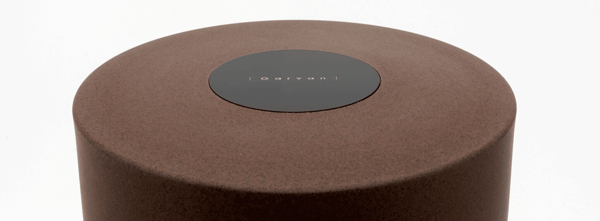 Brown cylindrical object with a dark circular emblem on top.