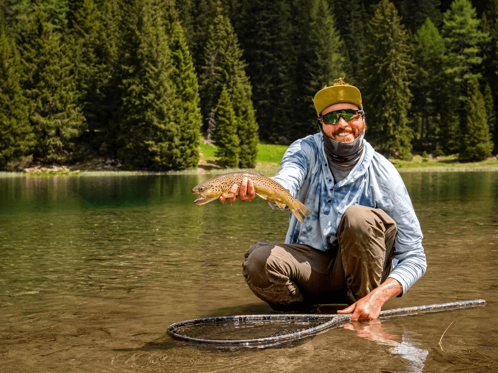 A fly fisherman hiking the SAT 221 trail in the Brenta Dolomites, carrying gear toward the remote San Giuliano lakes for a backcountry expedition.