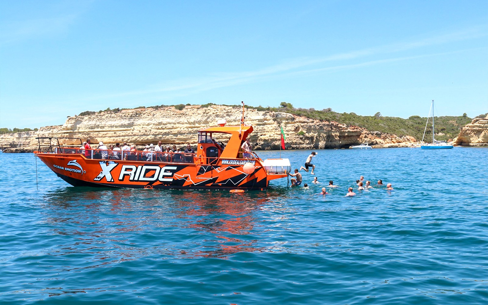 Tourists swimming near a boat during a guided tour of Benagil Caves and dolphin watching from Albufeira.