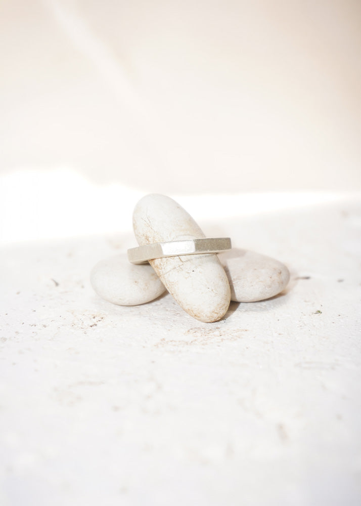 Silver ring on a white stone surface with a soft focus background