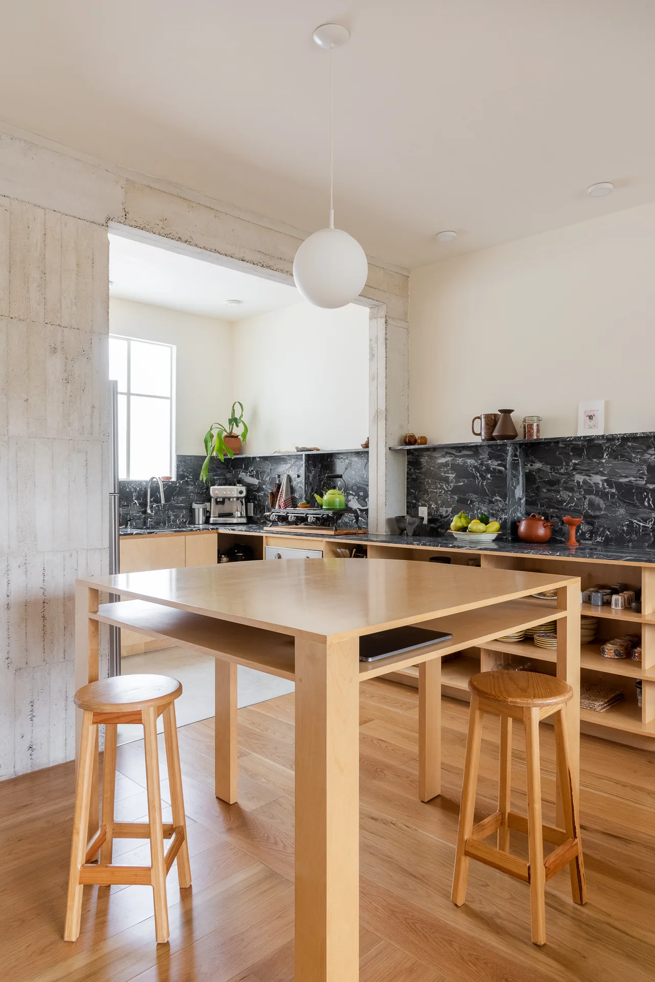Mesa alta de madera con bancos frente a la cocina al fondo