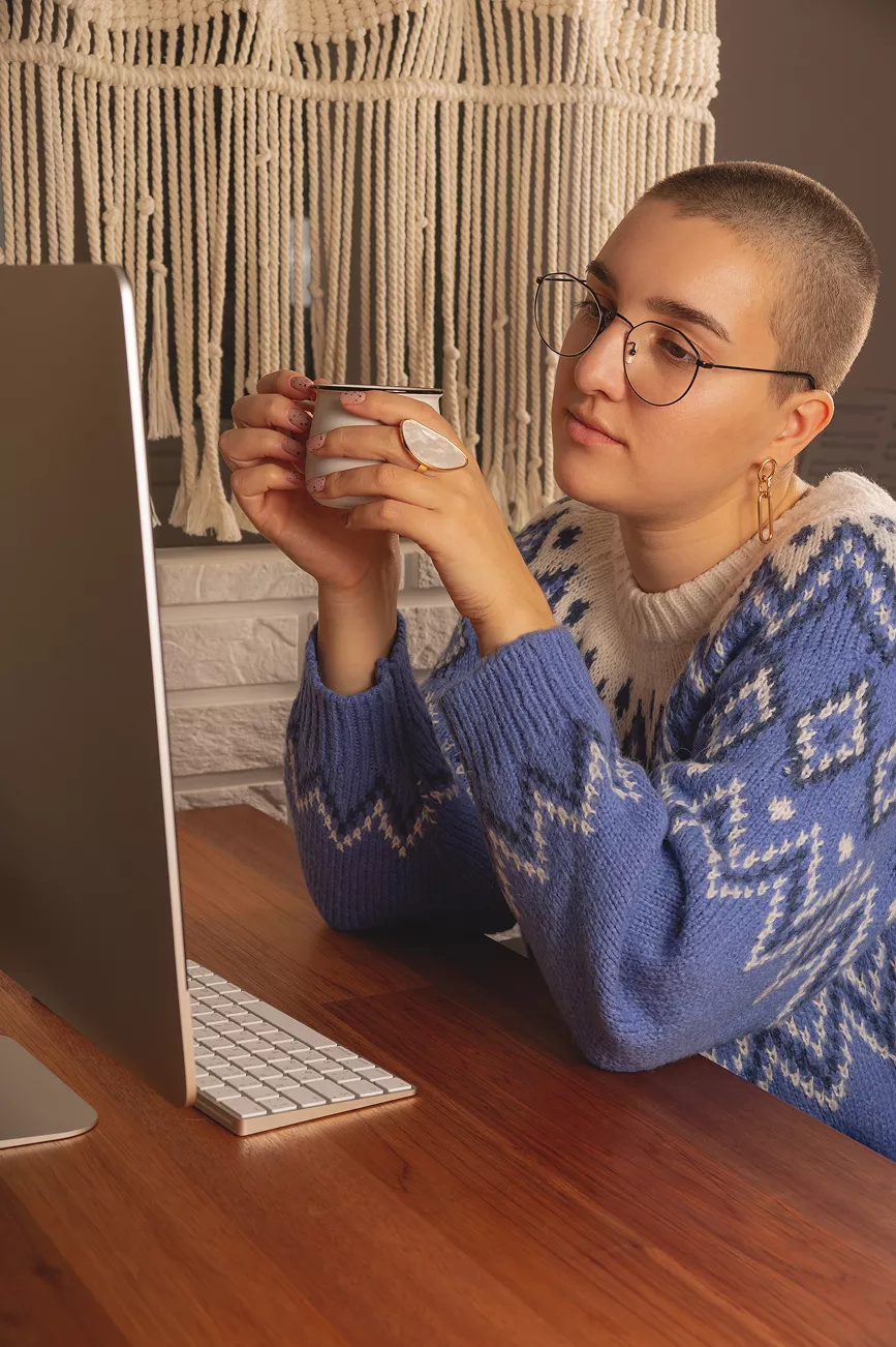 woman holding mug and looking a computer screen