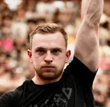 A person with curly hair and glasses, wearing an orange sweater, looks thoughtfully into the distance, resting their chin on their hand. Warm, cozy ambiance