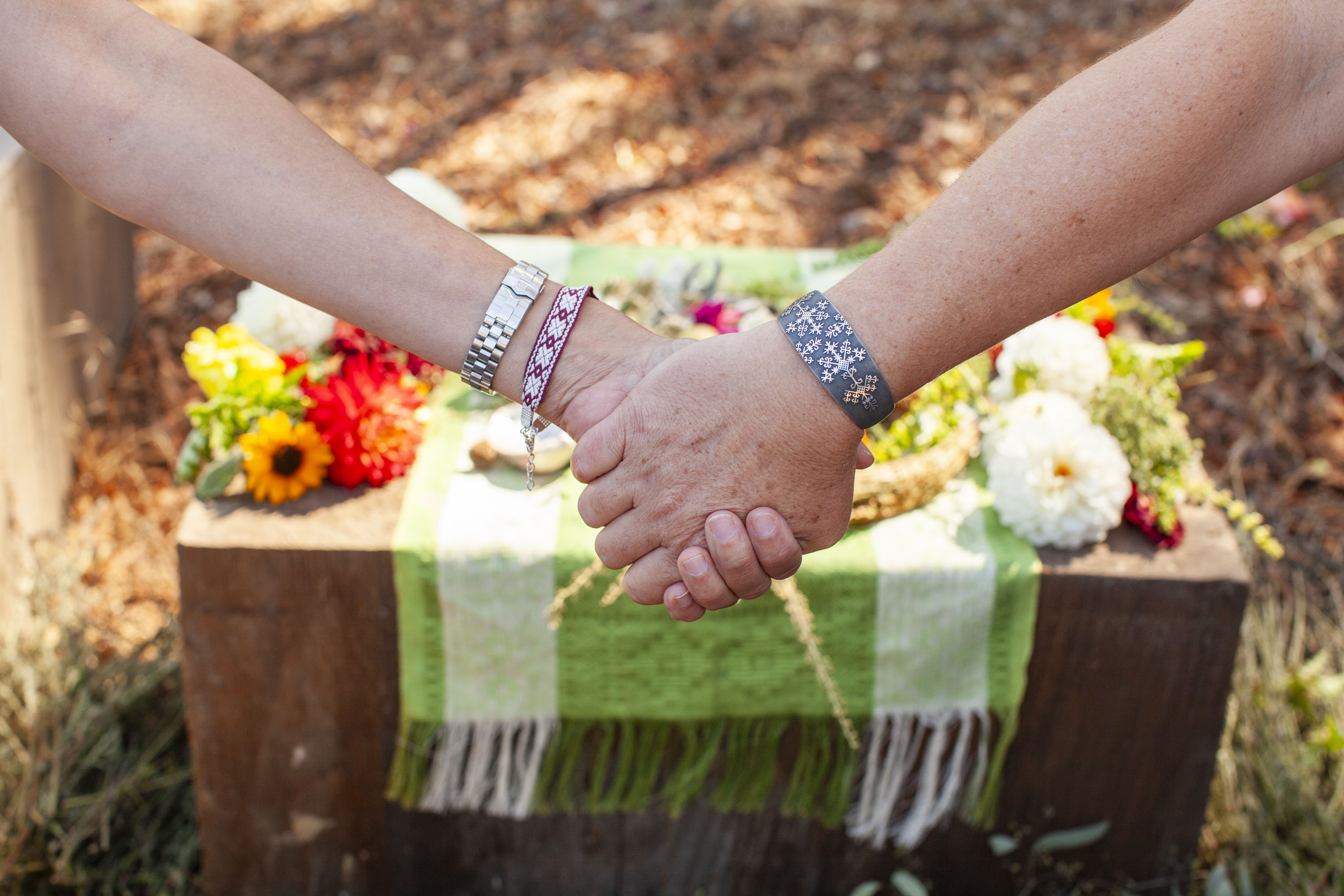 Two women holding hands in front of an altar