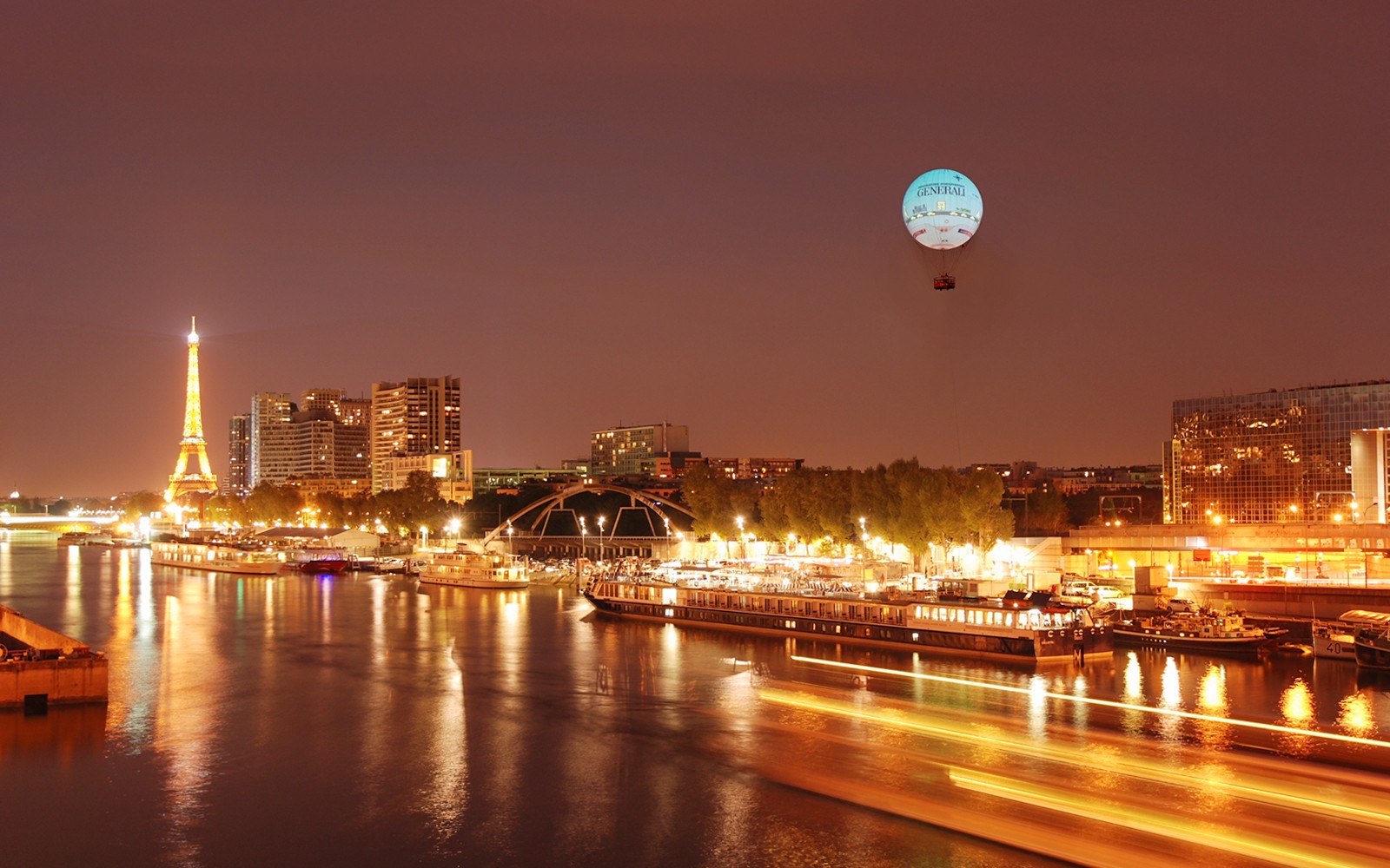 Ballon de Paris Generali floating over Seine River with Eiffel Tower in view.