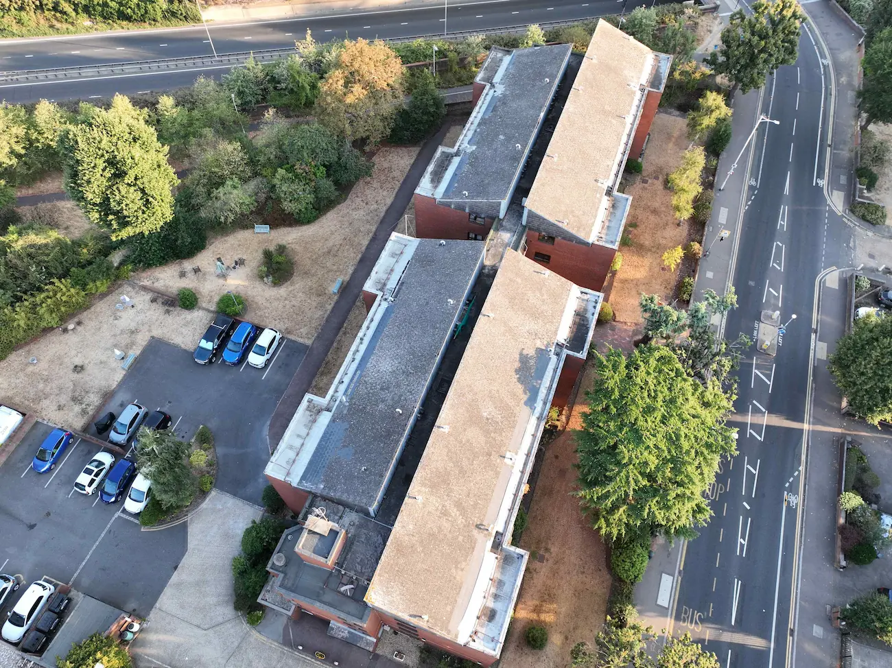 Aerial drone roof inspection view of a flat roof residential building block and parking area