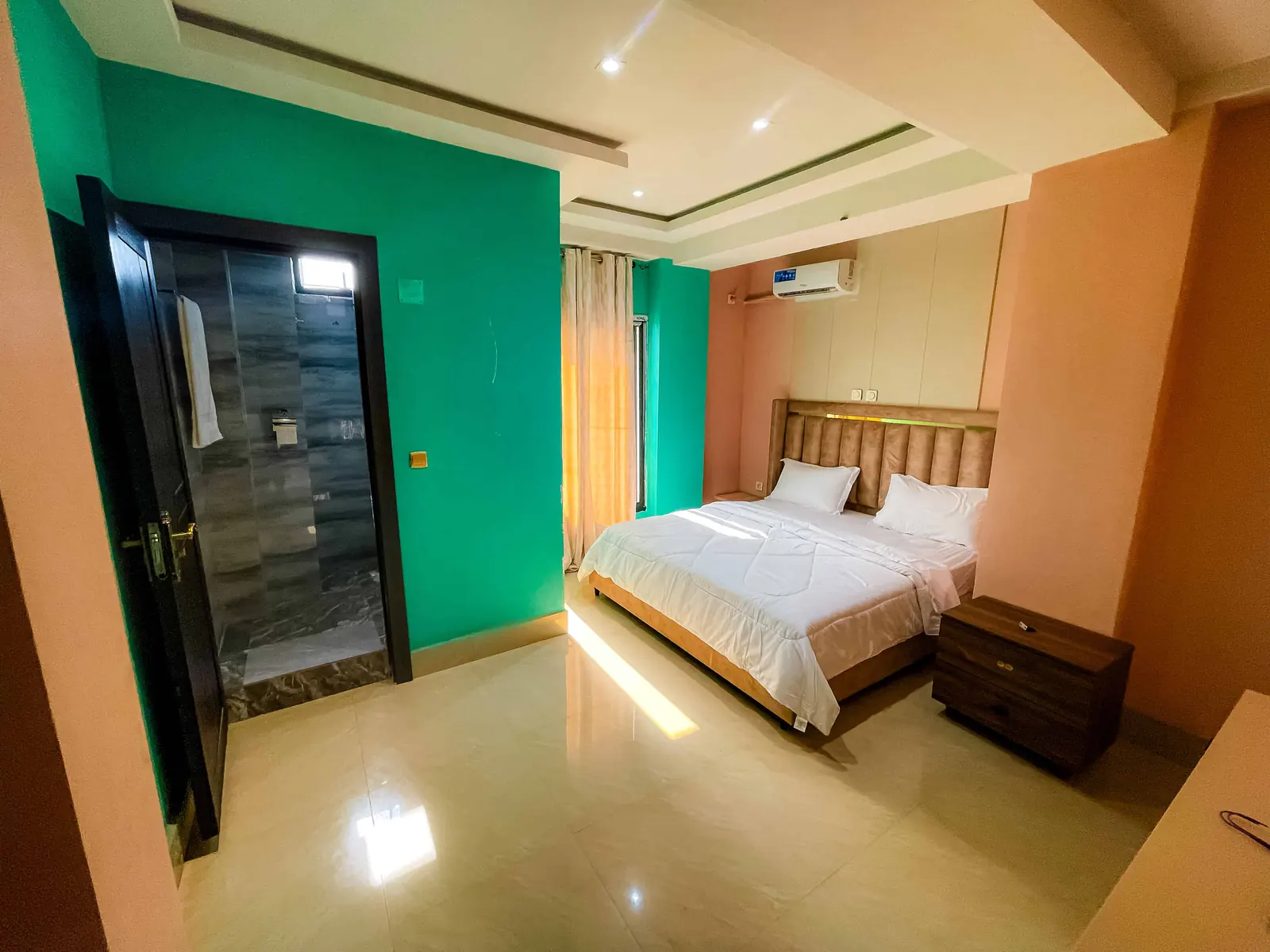 Chambre avec lit double, armoire à portes vitrées, rideaux clairs et mur turquoise.