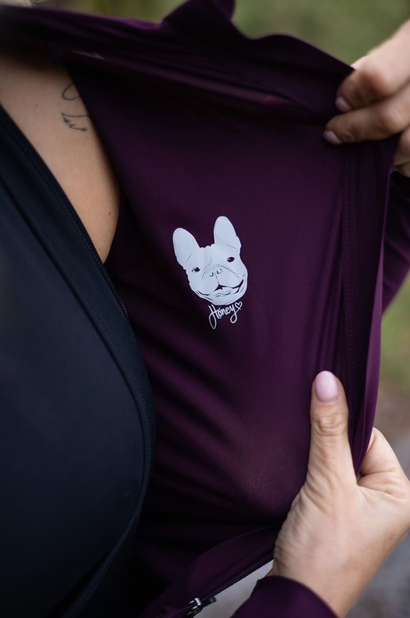 Close-up-of-dark-purple-cycling-top-pulled-open-to-reveal-the-white-French-Bulldog-graphic-and- Honey-text-printed-on-the-inside lining.