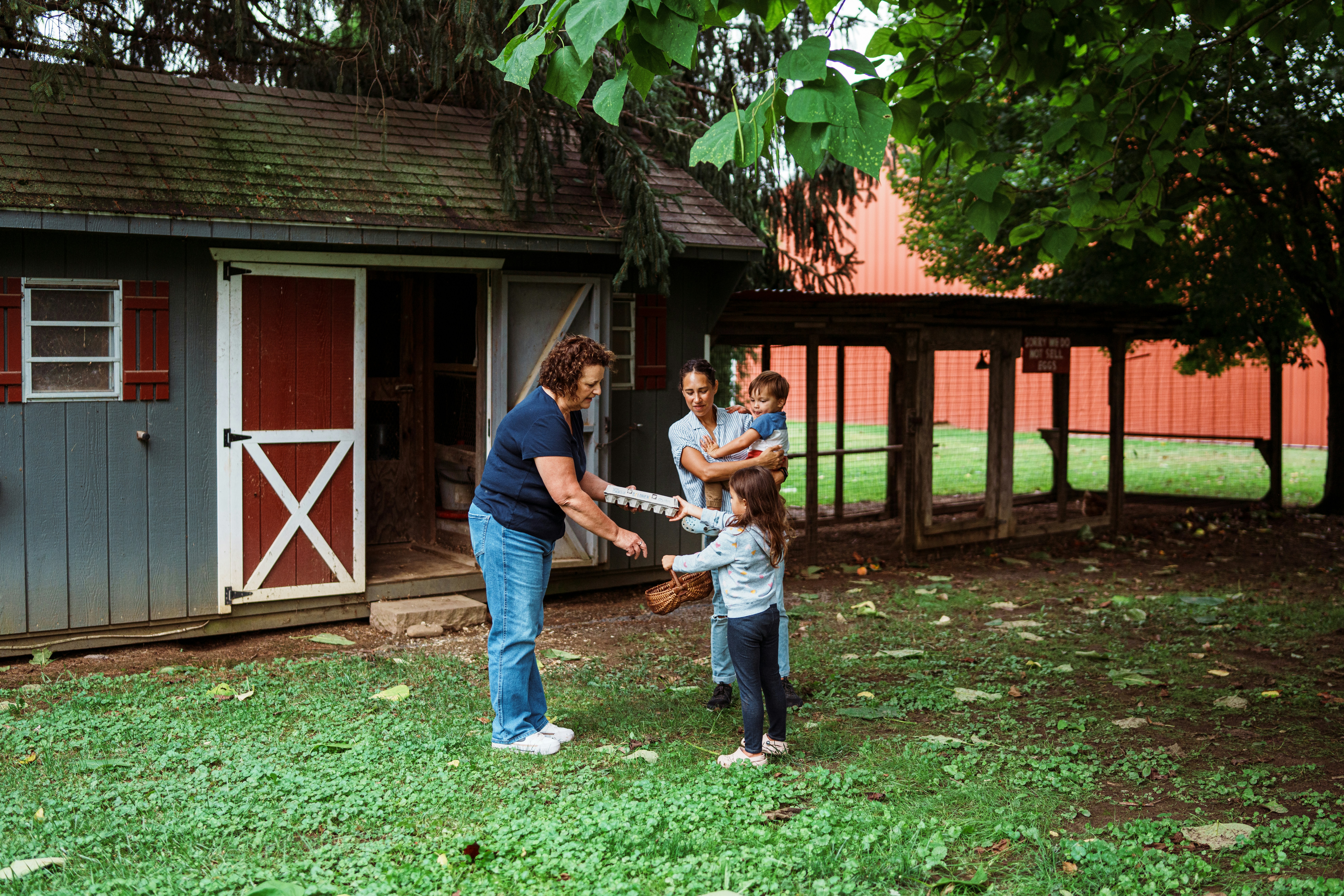 Family interacts with a woman near a shed.