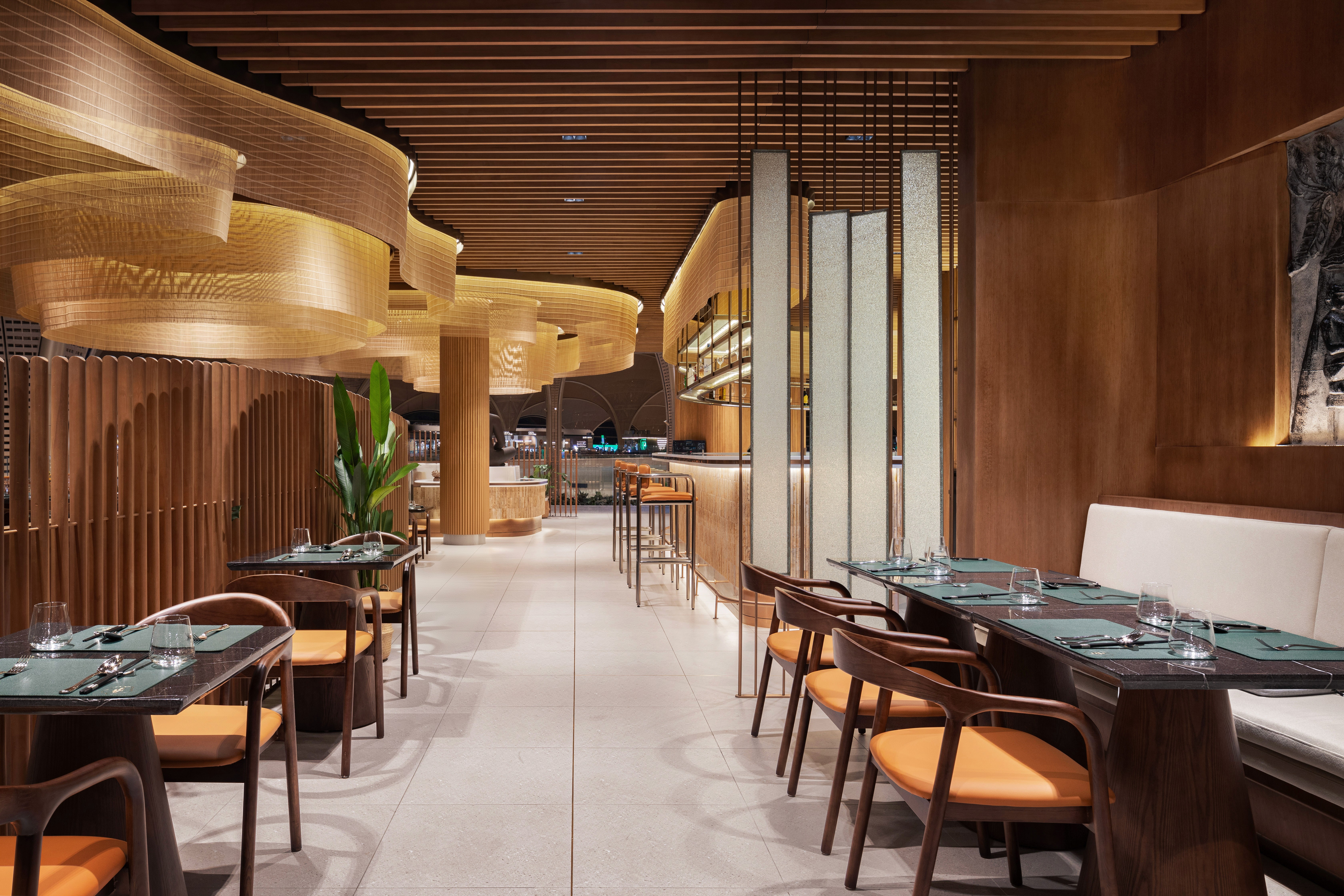 malis-restaurant-kti-interior-design Warm lighting and wooden slat ceilings in the Malis Restaurant dining area at Techo International Airport.