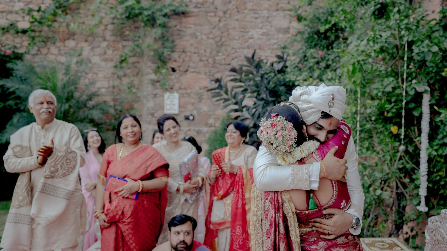 indian wedding couple emotional hug ceremony candid moment family background