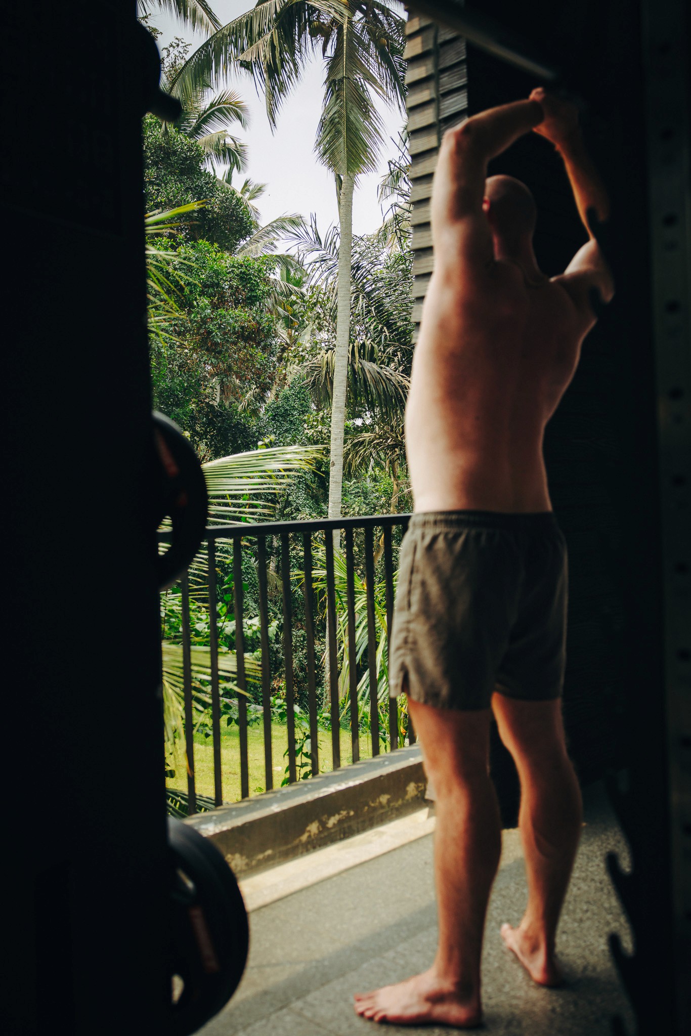 Ein Gast genießt den morgendlichen Ausblick vom Balkon im Ning Resort Ubud mit Blick auf den tropischen Regenwald