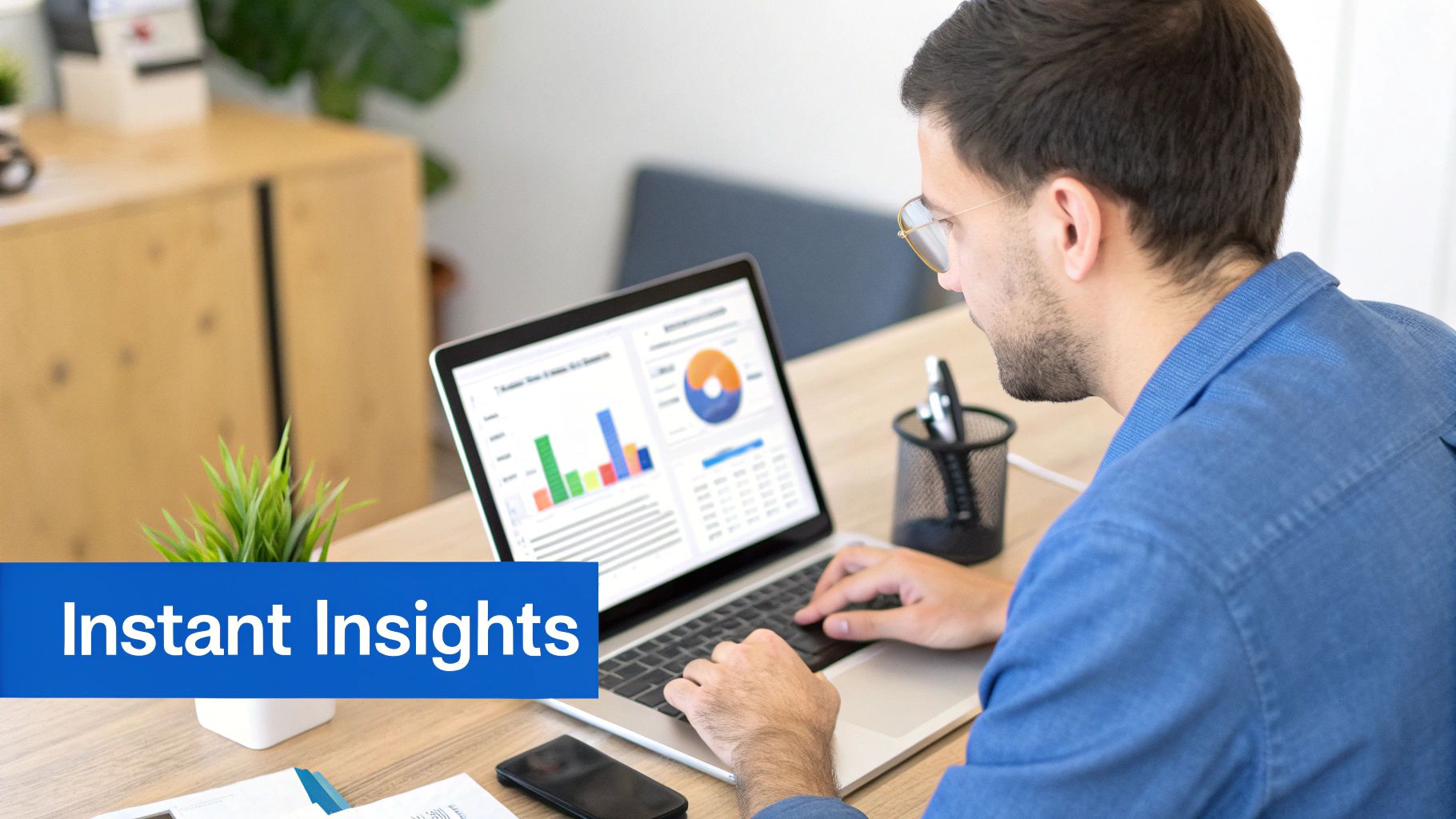 A man in a blue shirt works on a laptop displaying data analytics charts and graphs, with 