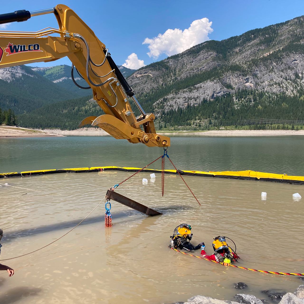Field crew conducting river survey and monitoring on Kananaskis River cobble bed with surveying equipment and riprap-stabilized banks in background