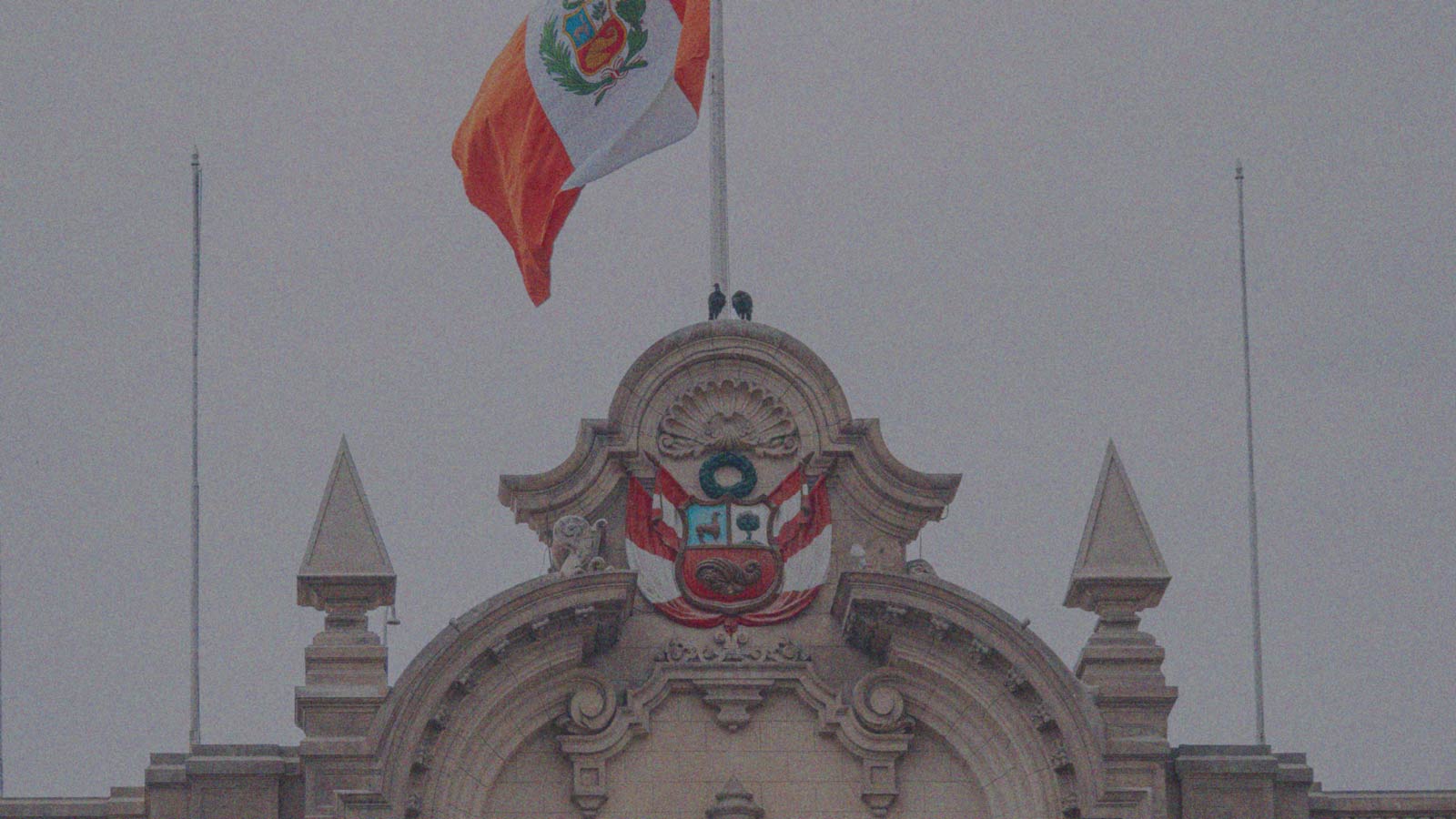 Foto que muestra una bandera peruana flameando en la parte superior de un edificio, en la columna de opinión El espejo peruano de IdeaPaís.
