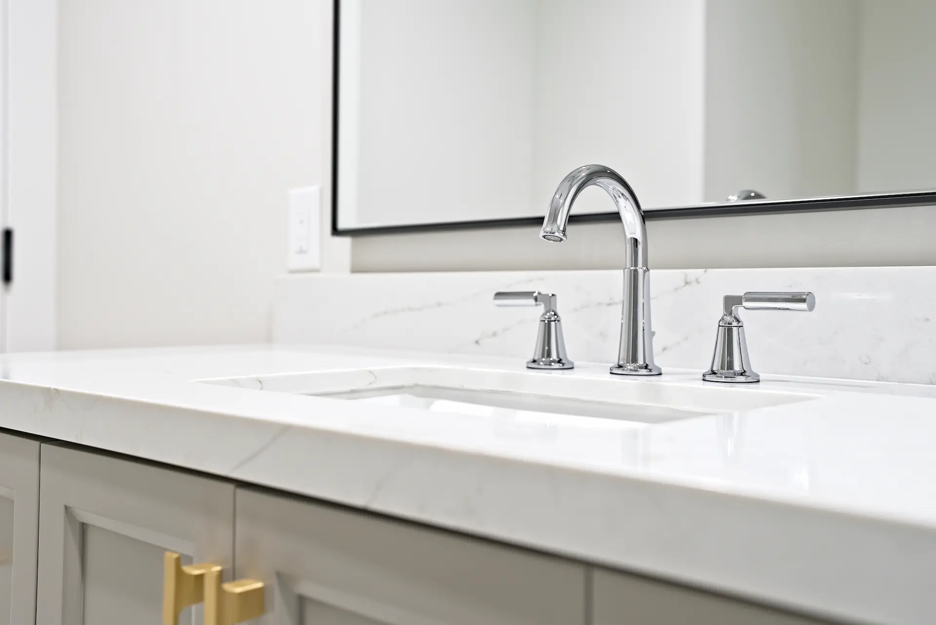 Close-up of the Jack and Jill bathroom sink, highlighting the sleek design and satin brass hardware, merging style and utility in the Dana Point Full Remodel. Photo by Todd Huge.