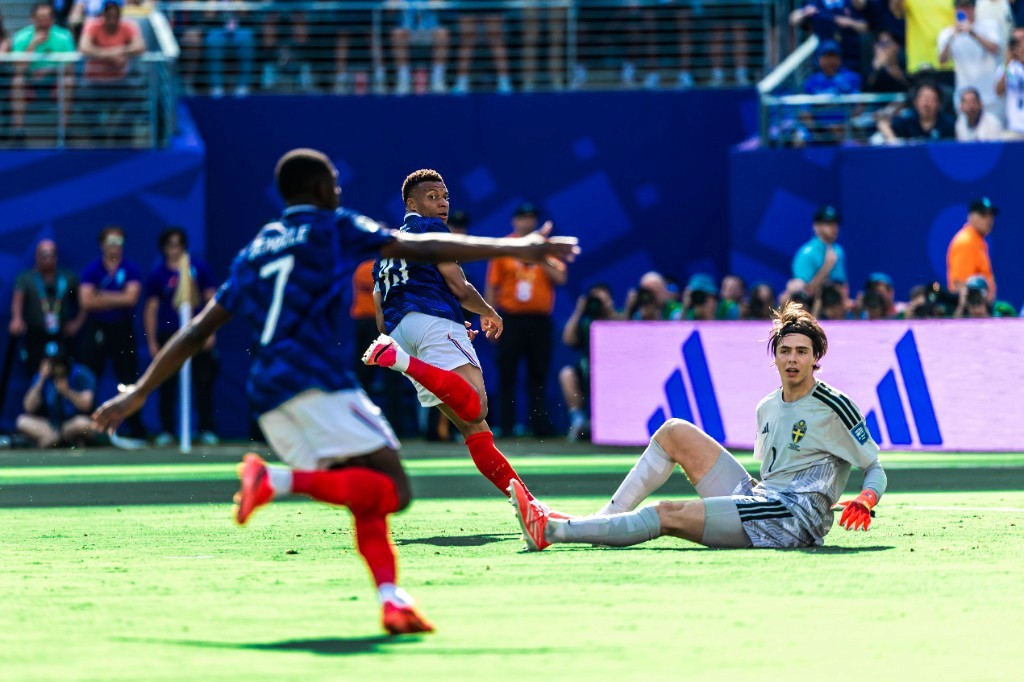 Kylian Mbappé shoots as Sweden's goalkeeper is beaten during France's World Cup Round of 32 win