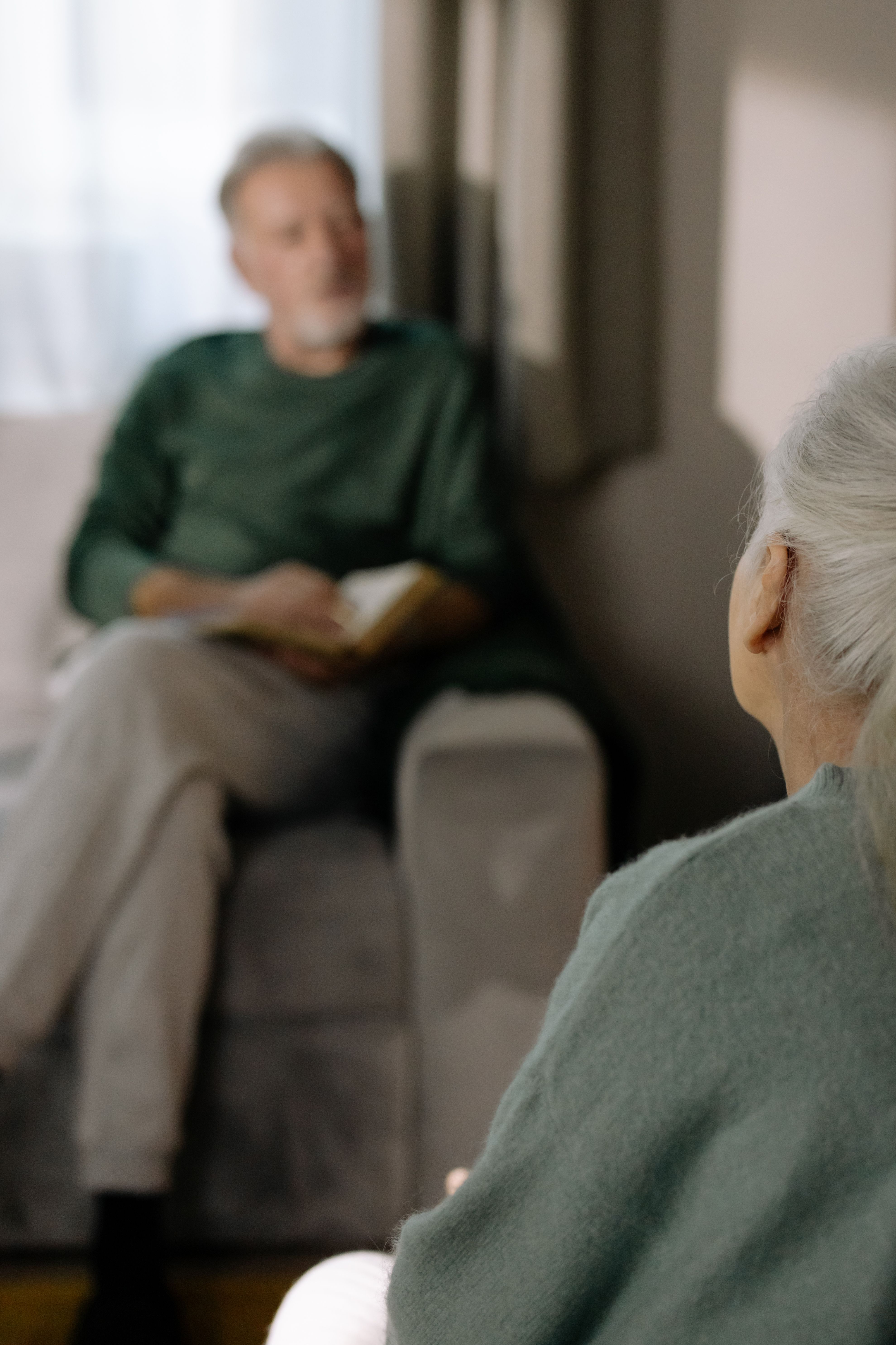 two woman sits on sofa chairs inside house