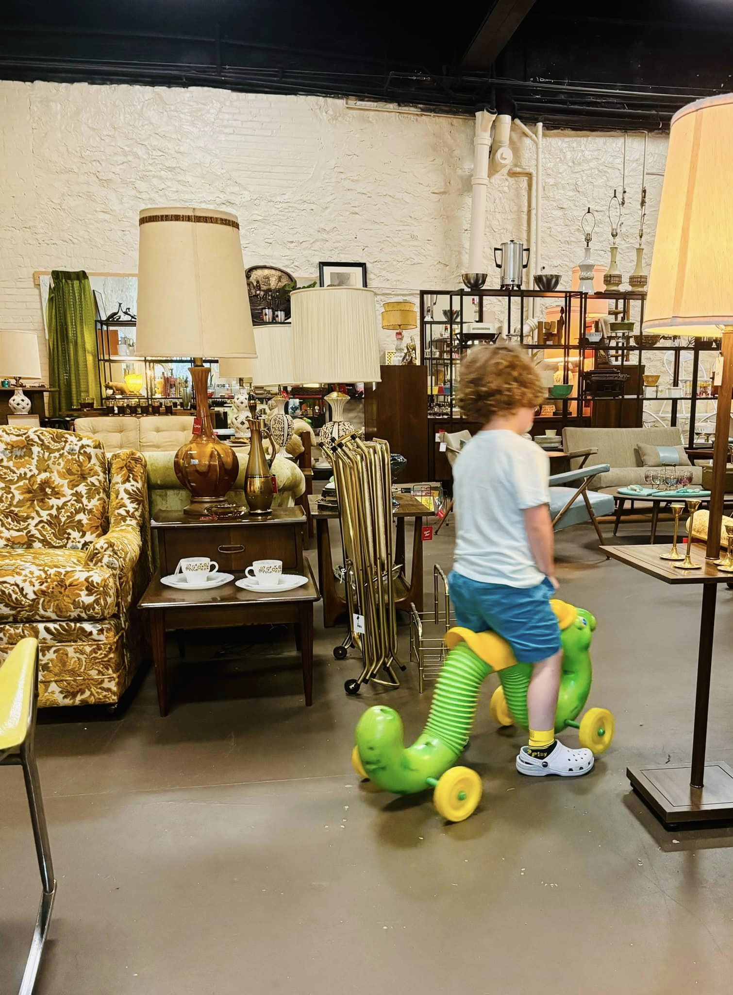 Boy on a vintage inch worm toy in a mcm vintage store