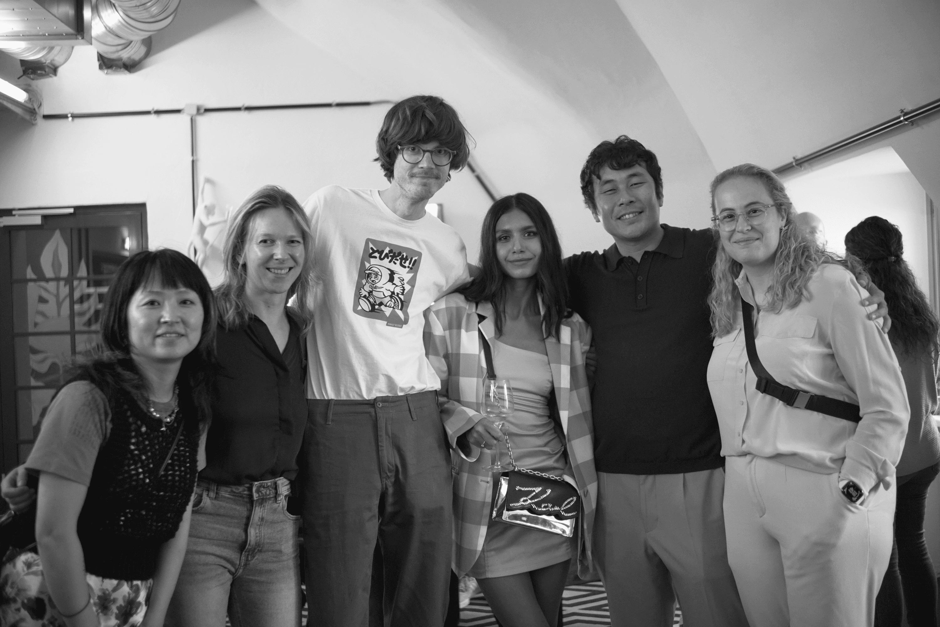 Black and white photo of two people looking at a computer screen with papers on wall
