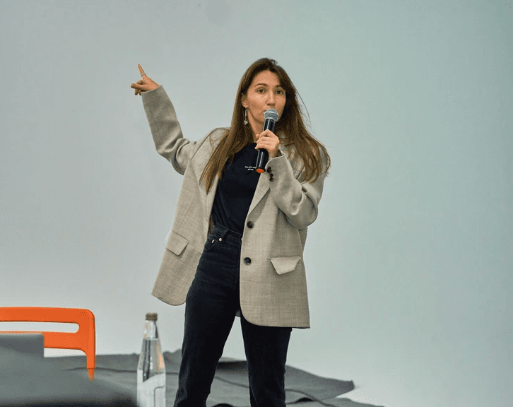 A woman standing in front of a projector screen giving a presentation