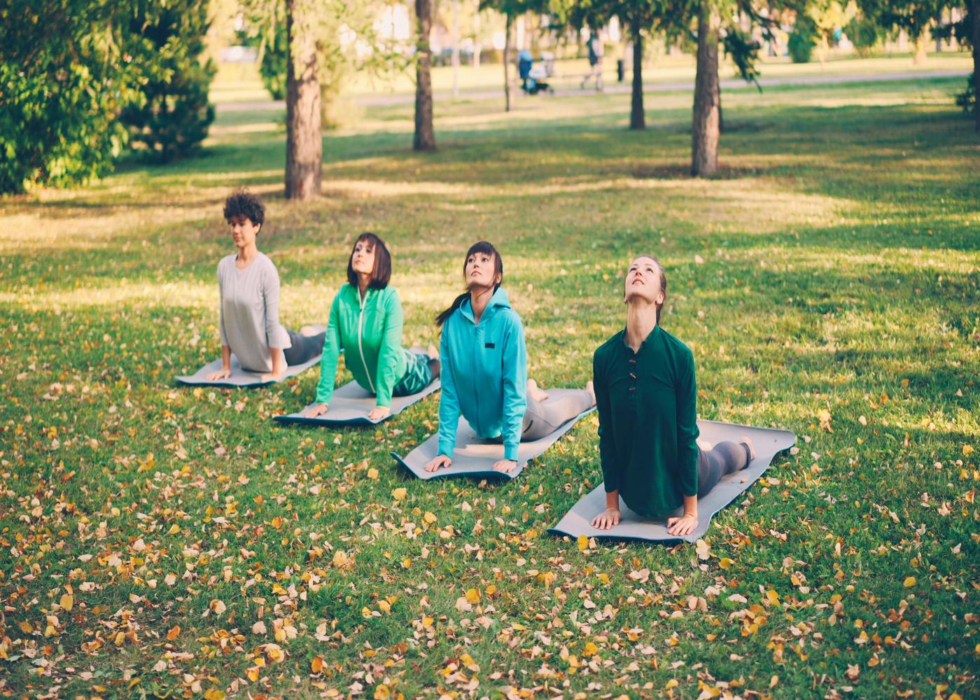 Four women outdoors doing yoga on yoga mats