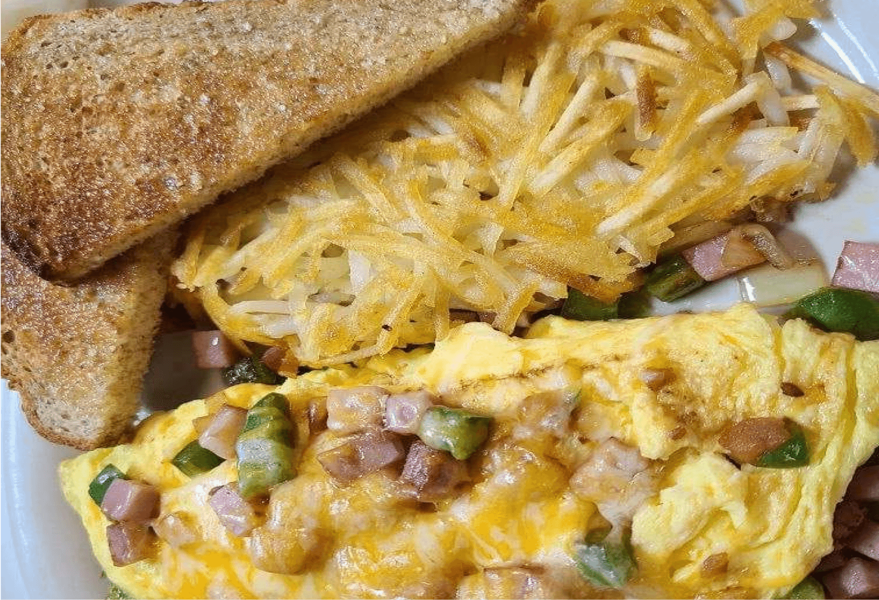 A custom omelet filled with mixed vegetables and meats, served with crispy hash browns and toast at Engine House Cafe.