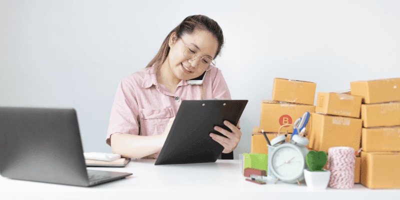 Seorang wanita sedang menjawab panggilan telefon sambil mencatat info pada kertas.