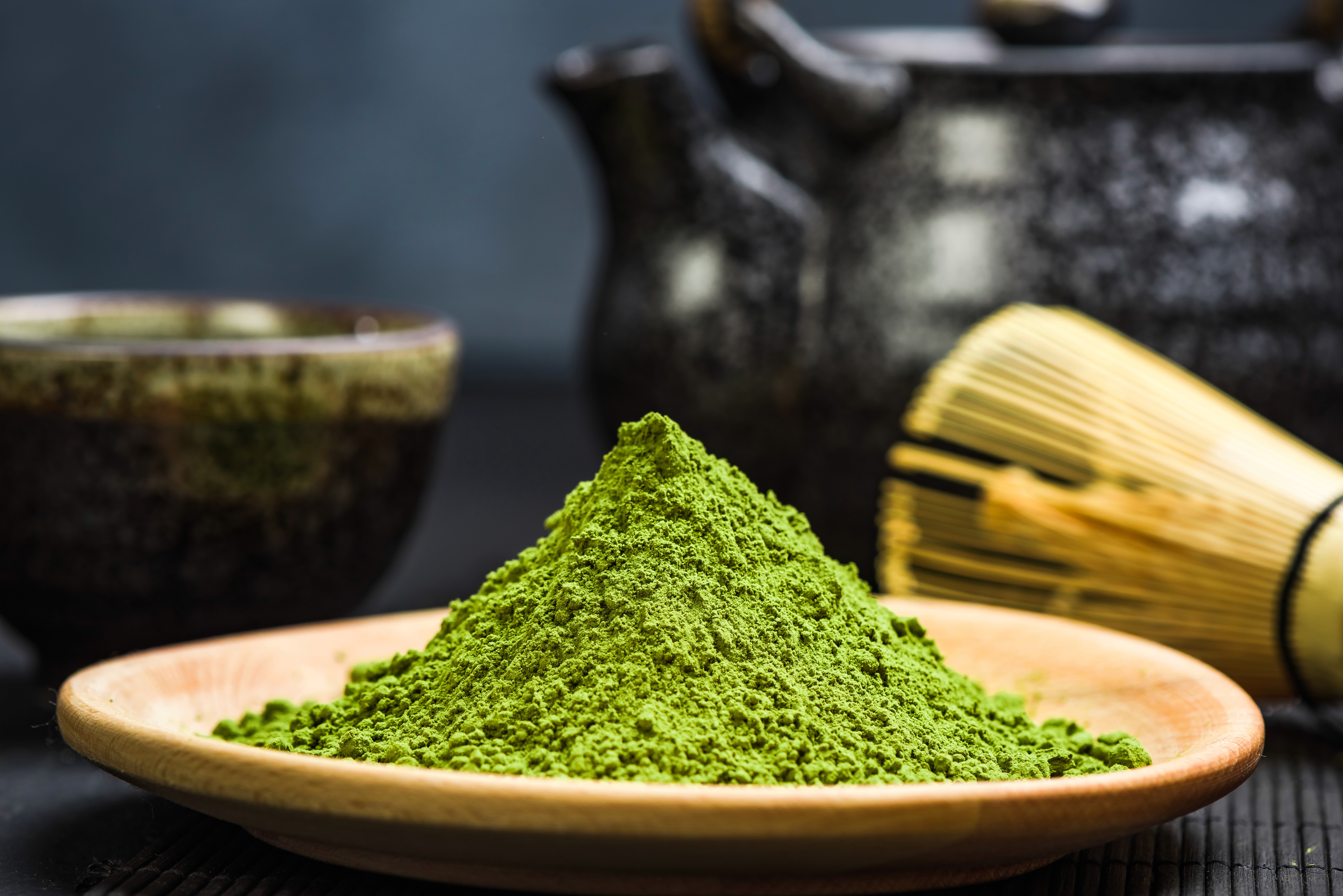 Ceremonial matcha in a bowl next to a bamboo whisker