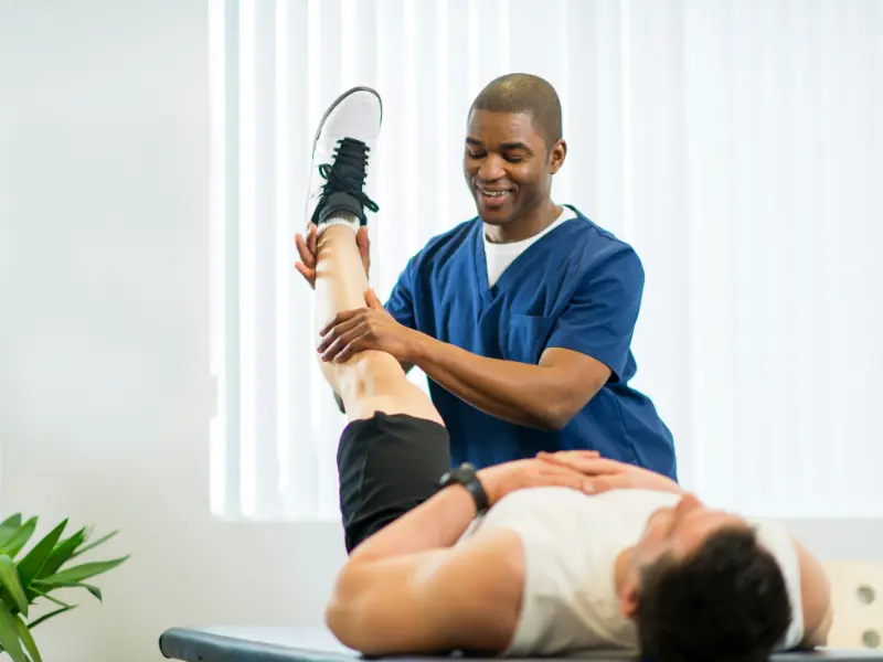A physiotherapist stretching a patient's leg in a clinic
