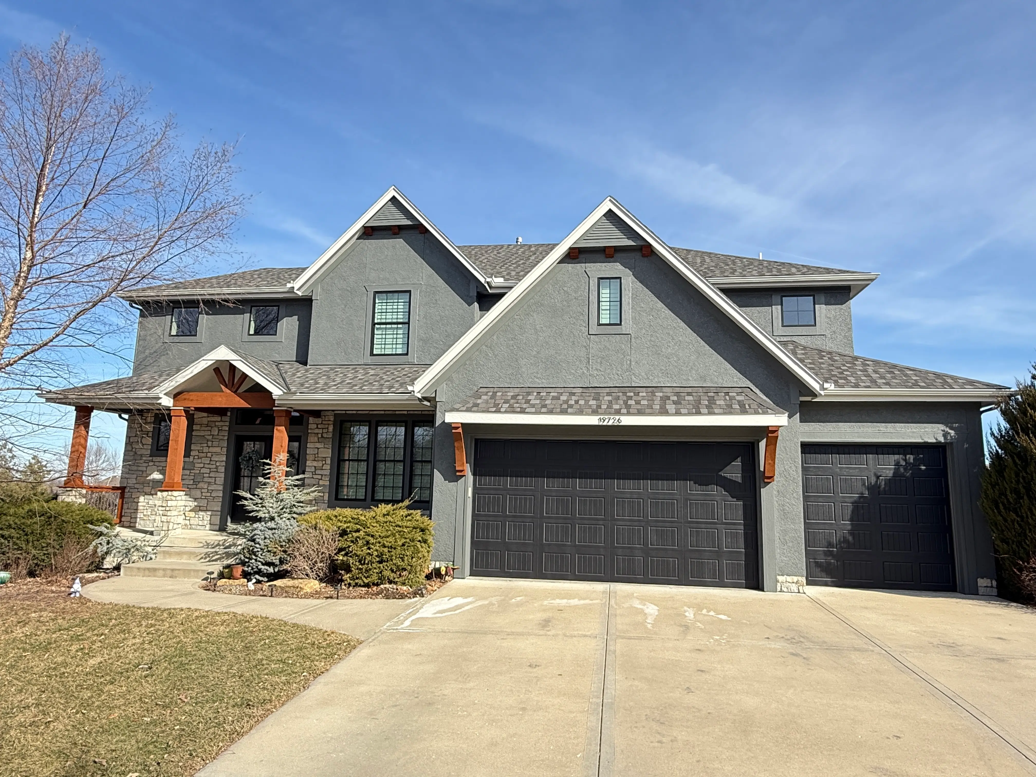 An image of a newly painted grey house with black accents and cedar wood.