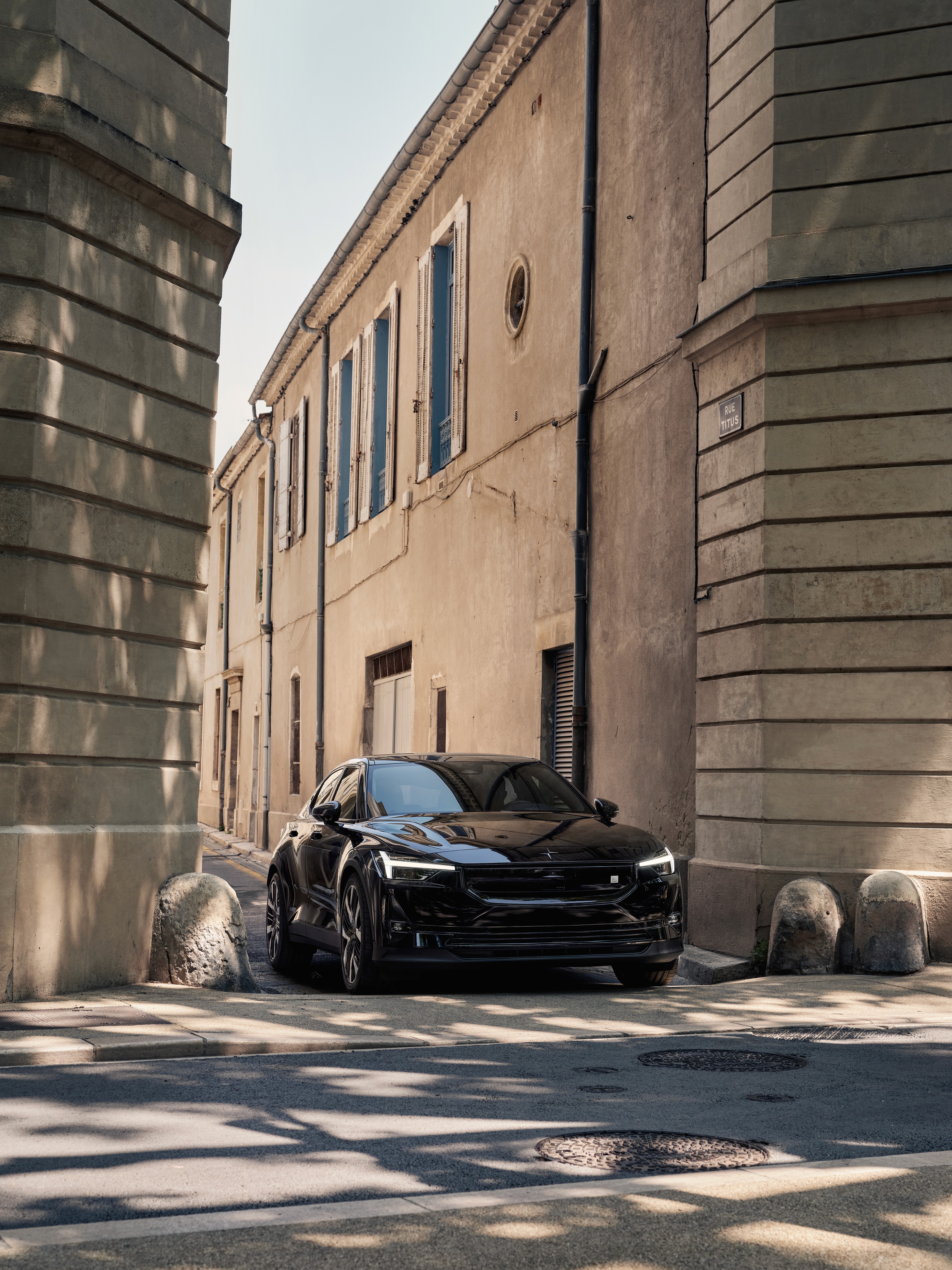 Polestar 2 noire garée dans une rue étroite bordée d’immeubles anciens