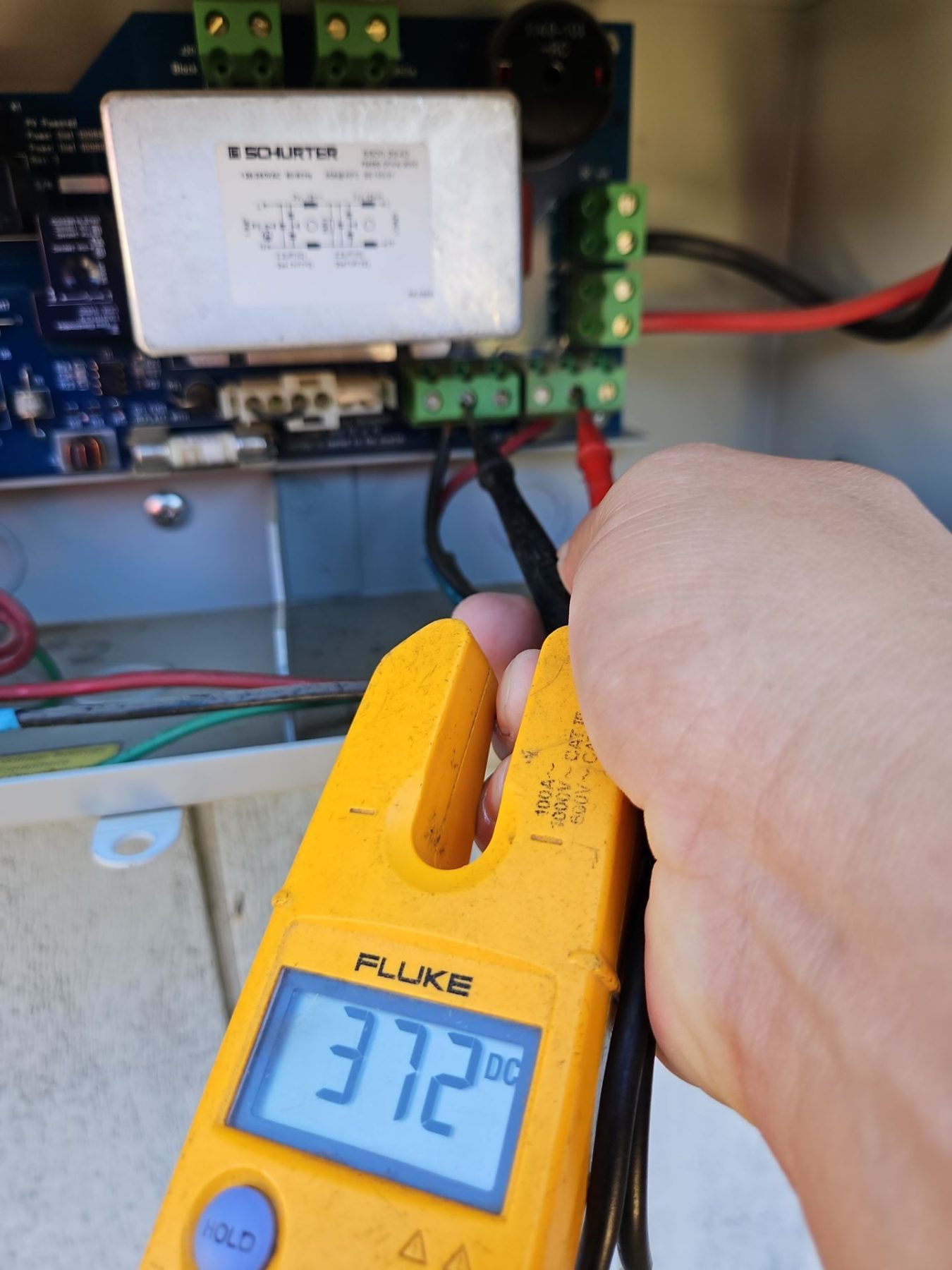 Technician testing inverter terminals with a clamp meter