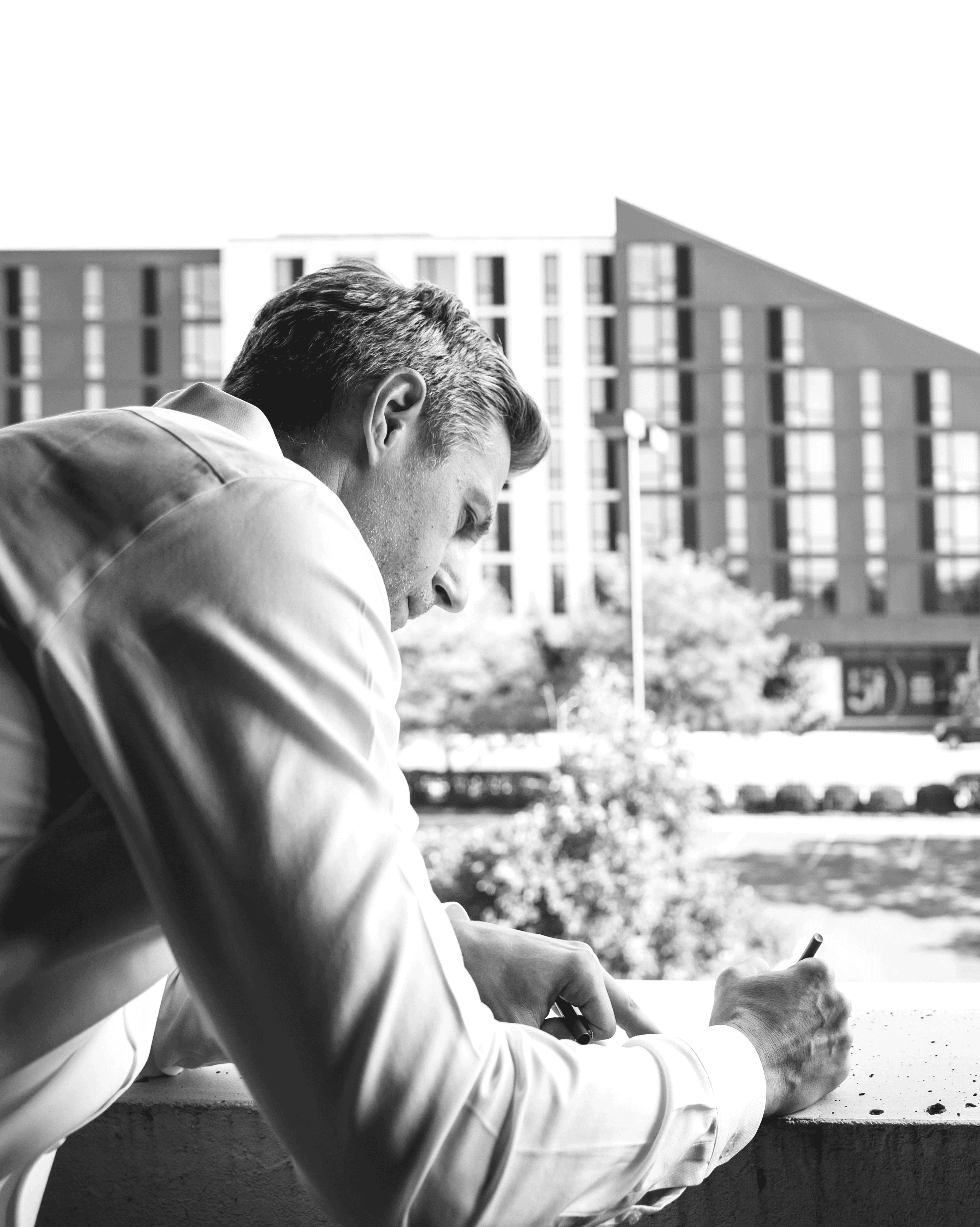 Close-up portrait of a person wearing a gray insulated hooded jacket with the hood up, showing their face framed by the hood against a light background.