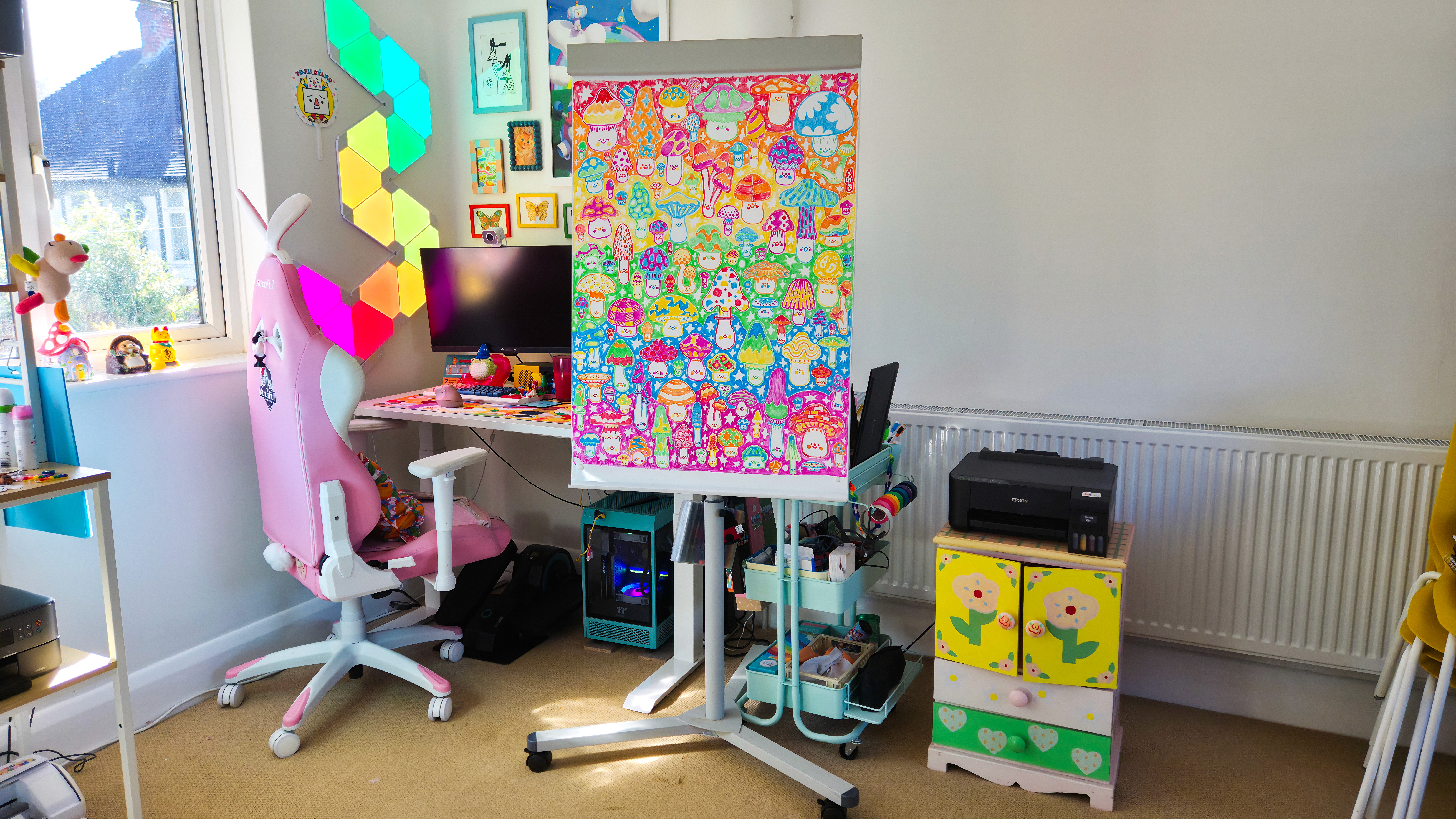 A large, standing whiteboard sits by a computer desk and other office furniture. The whiteboard is covered in a bright illustration of dozens of mushrooms.